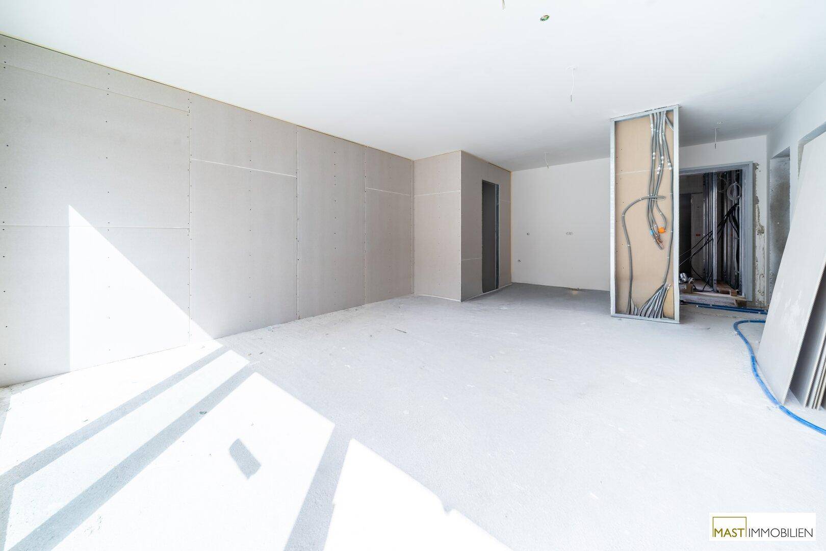 Rohbau eines Zimmers mit Trockenbauwänden und sichtbaren Elektroinstallationen.