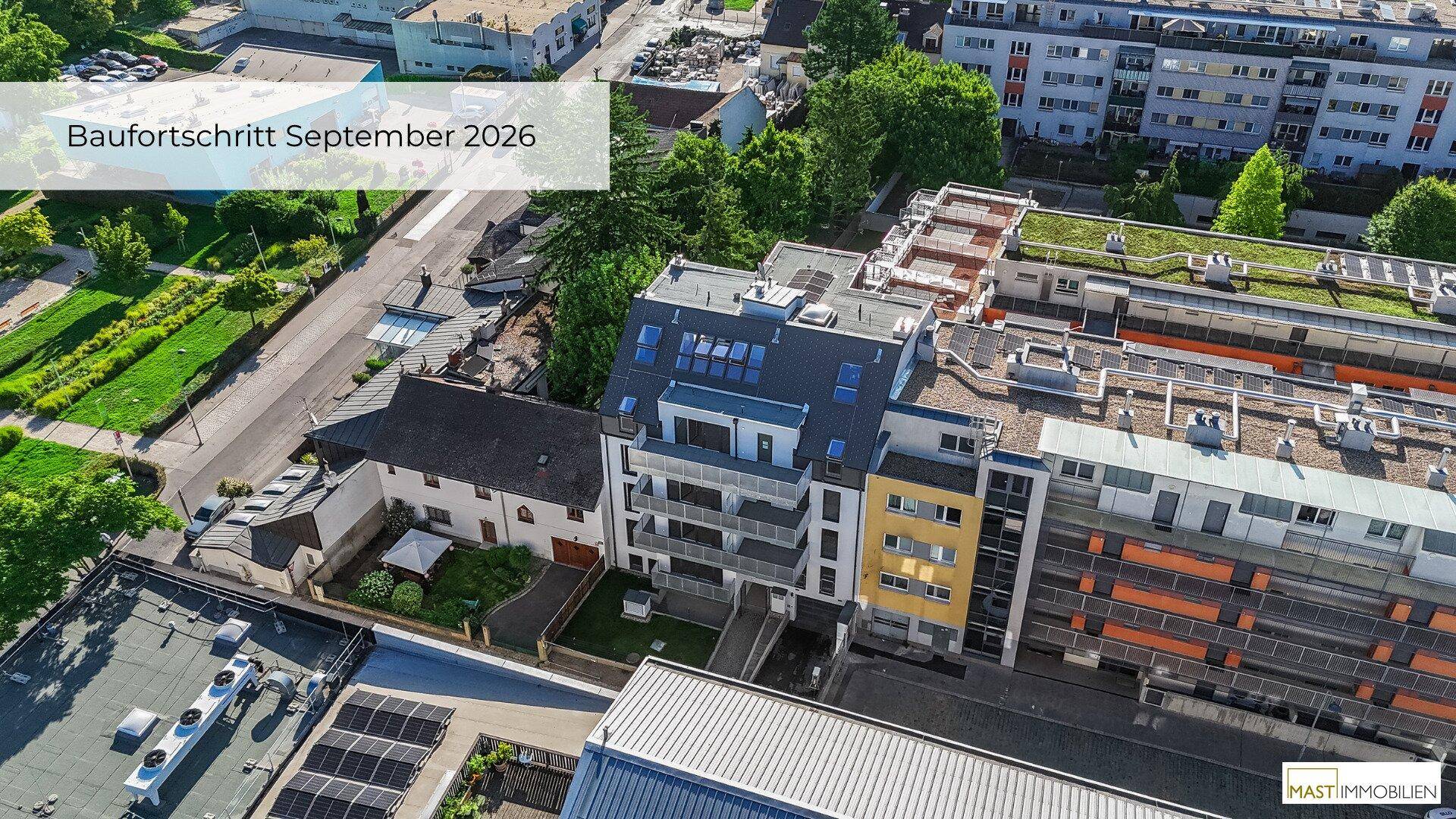 Luftaufnahme eines modernen Wohnkomplexes mit Balkonen und umliegender Grünfläche in städtischer Umgebung.