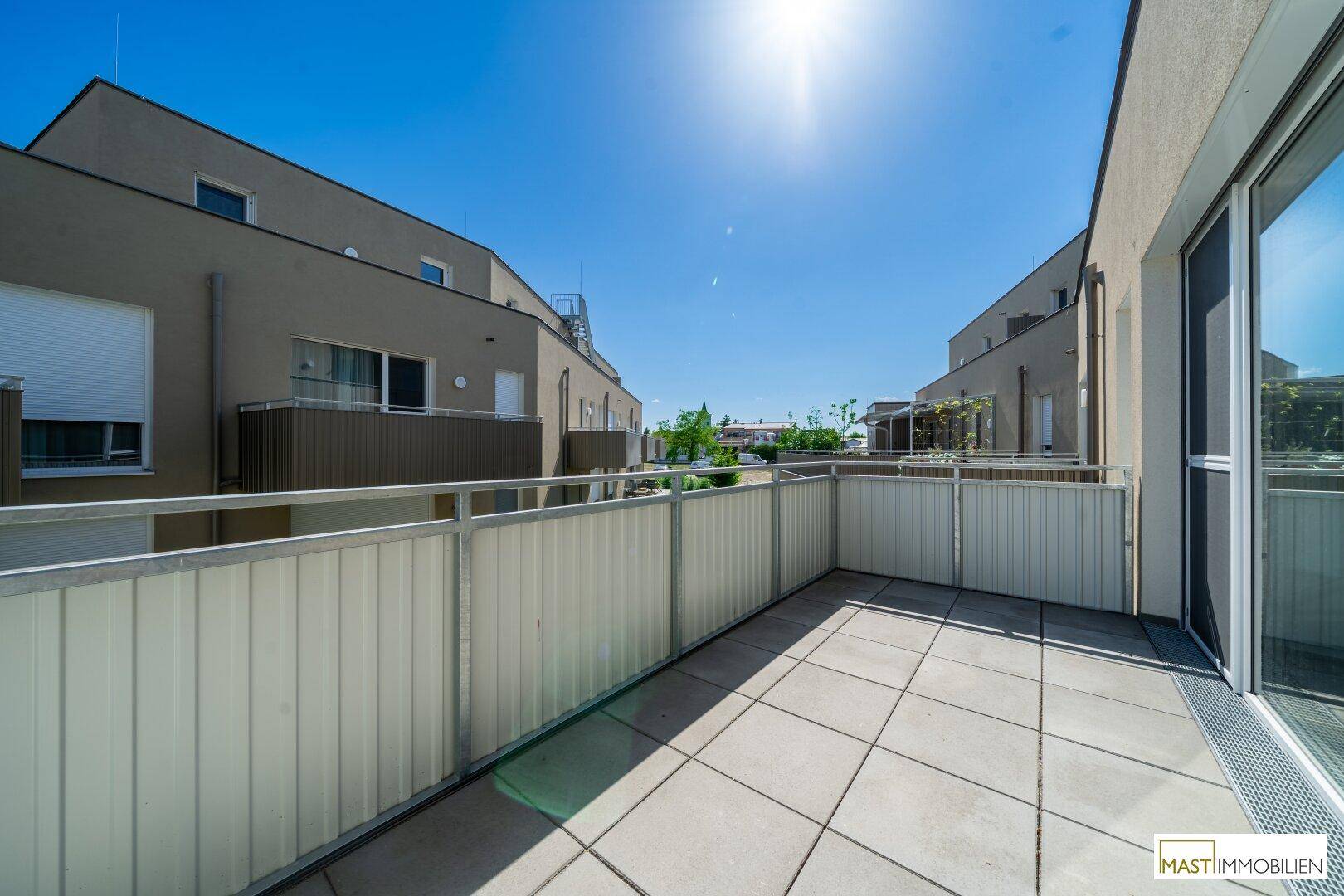 Sonniger Balkon mit Fliesenboden und Metallgeländer, bietet einen angenehmen Außenbereich.