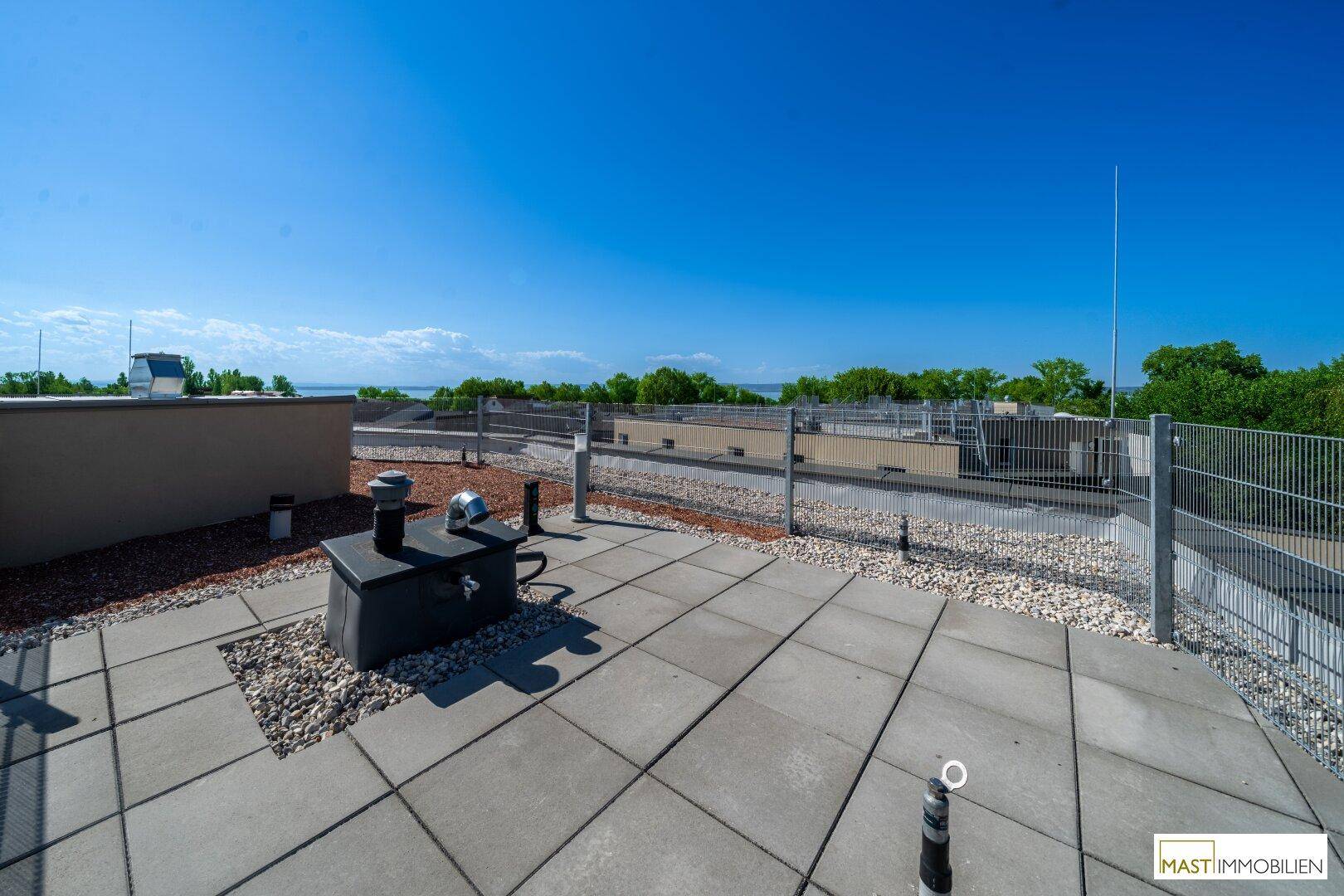 Gepflasterter Bereich auf der Dachterrasse mit Kiesumrandung und weitem Blick.