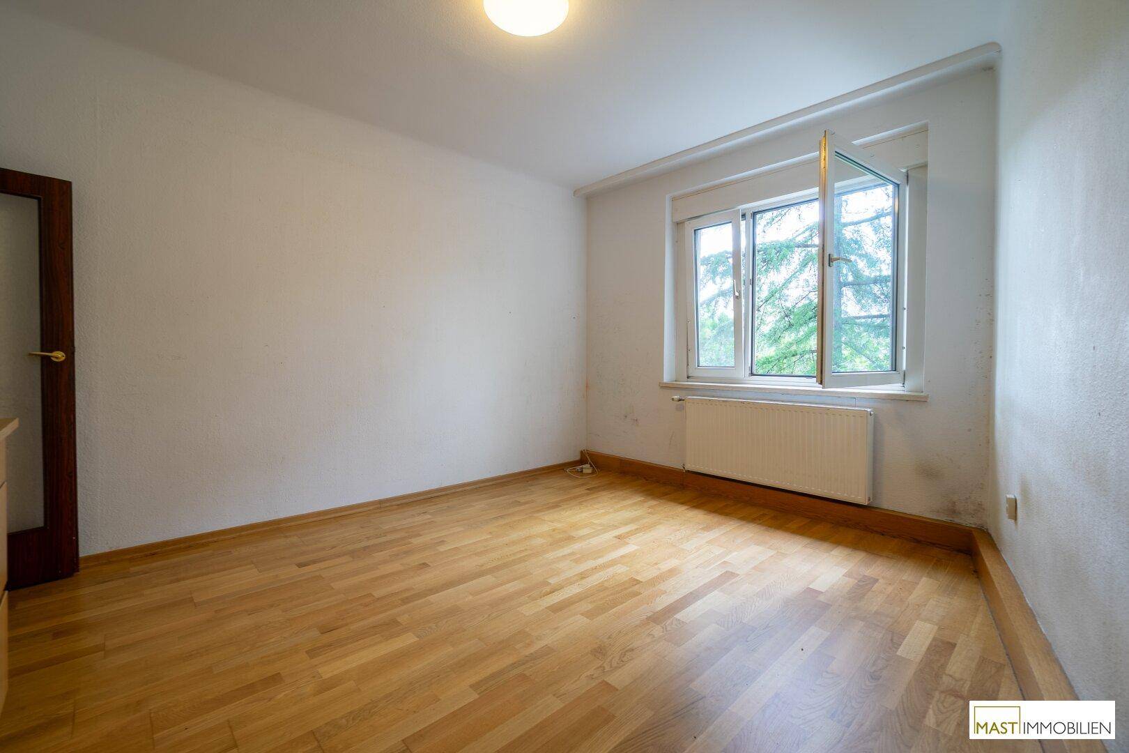 Geräumiges Schlafzimmer mit Laminatboden und einem Fenster, das den Raum erhellt.