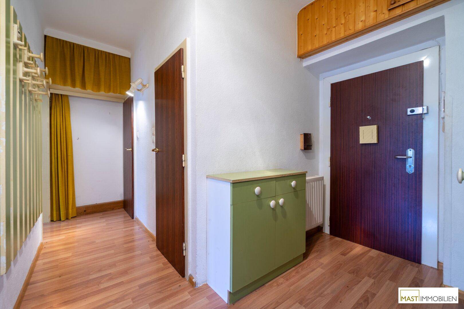 Flur mit Laminatboden, einem farbigen Schrank und Zugang zu verschiedenen Räumen.