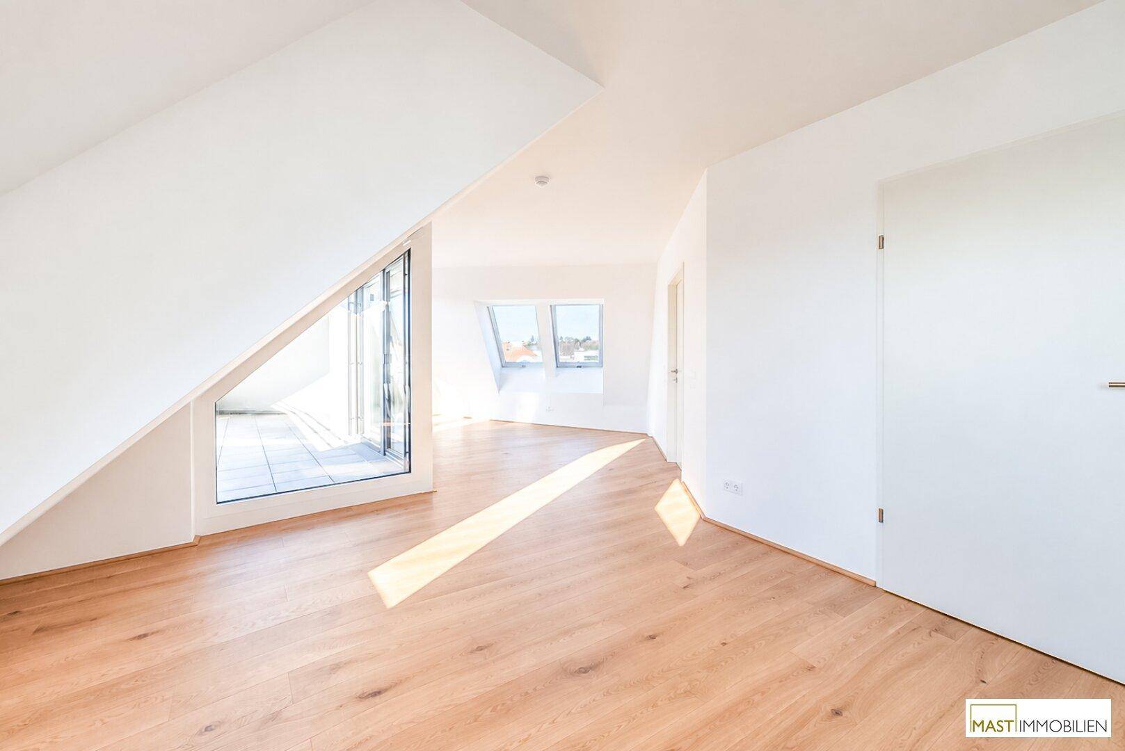 Offener, lichtdurchfluteter Raum im Dachgeschoss mit Holzboden und Zugang zur Terrasse.