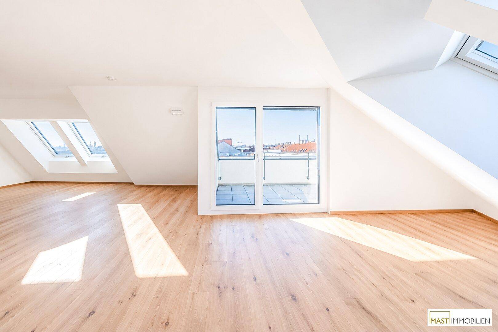 Heller Dachgeschossraum mit Holzboden und großen Fenstern, bietet Zugang zu einer sonnigen Terrasse.