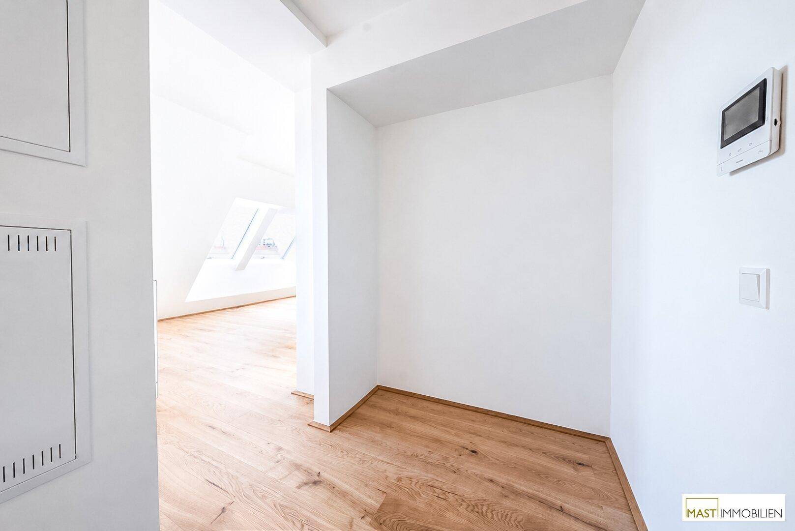 Heller Flur mit Holzboden und Gegensprechanlage, verbindet die verschiedenen Wohnbereiche.