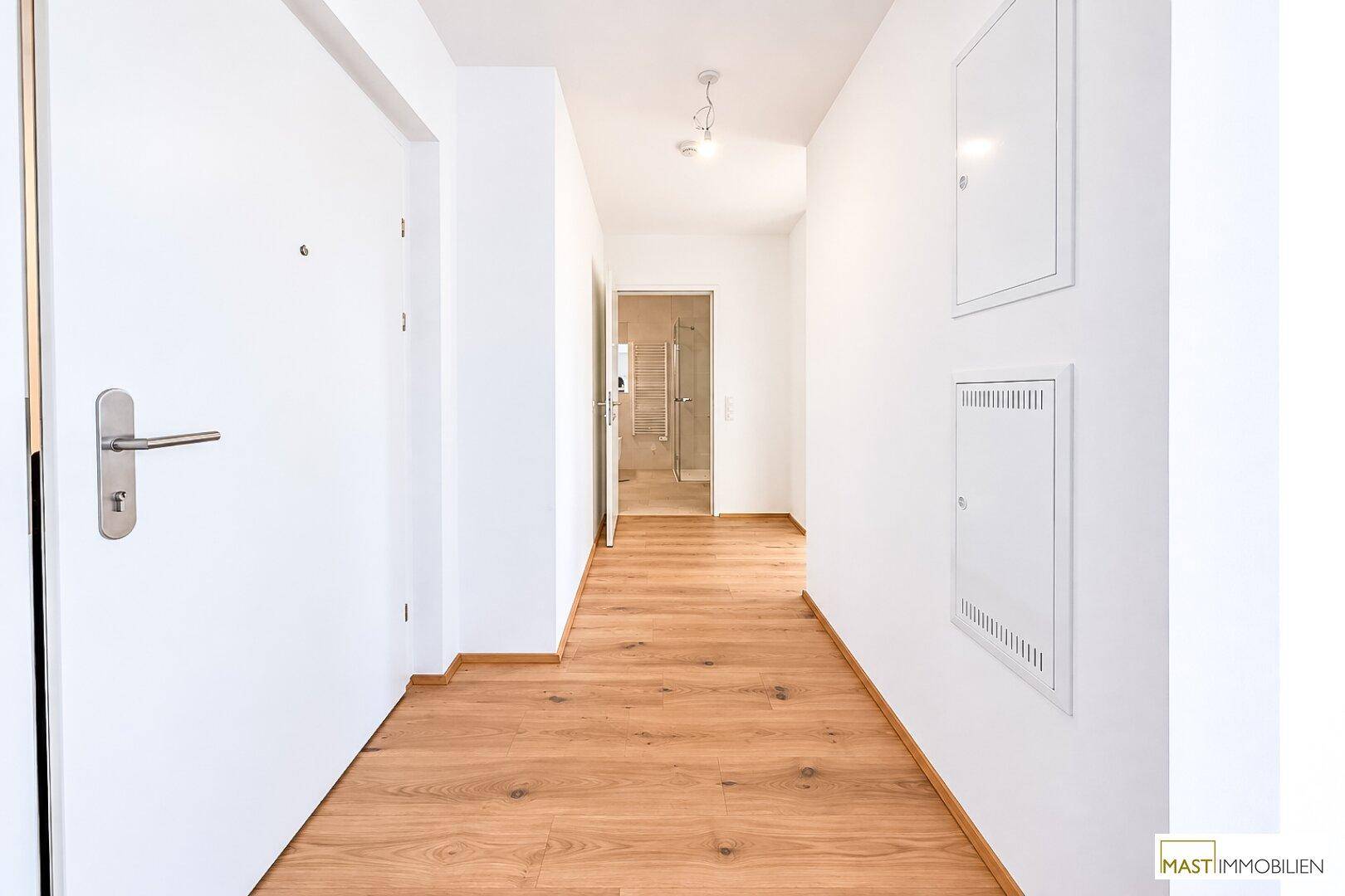 Langer Flur mit Holzboden, der zu einem Badezimmer und weiteren Zimmern führt.