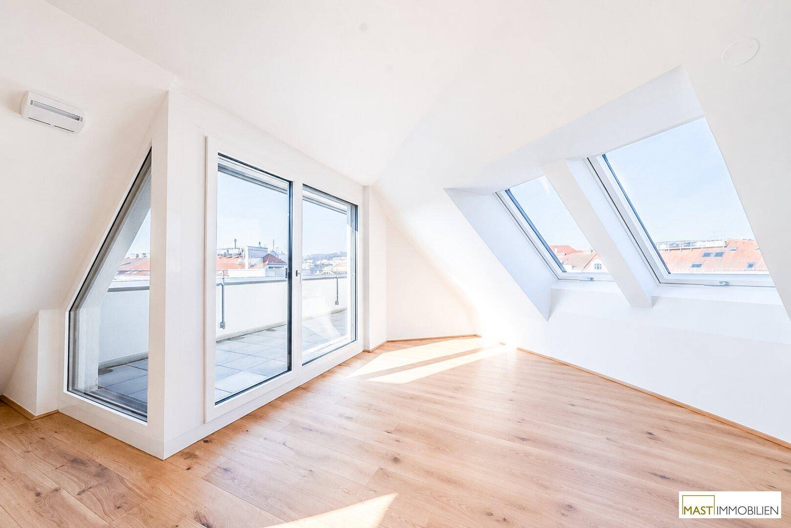 Geräumiger, heller Raum im Dachgeschoss mit Holzboden und Zugang zu einer sonnigen Terrasse.