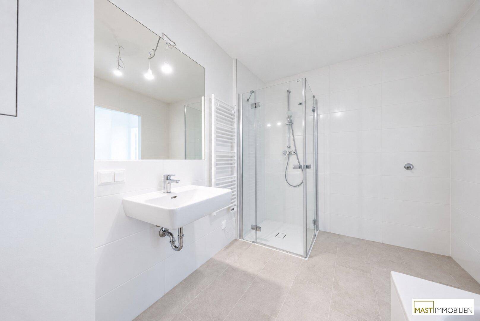 Helles Badezimmer mit moderner Dusche, Waschbecken und großem Spiegel, in neutralen Farbtönen.