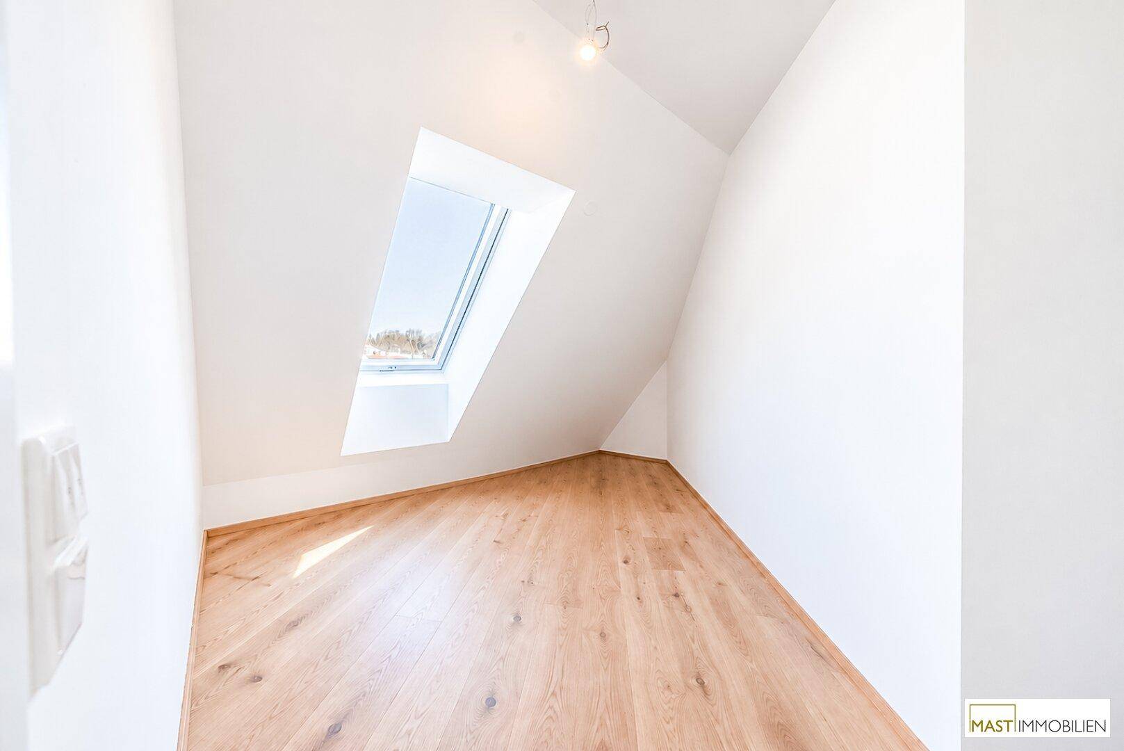 Kleineres Zimmer im Dachgeschoss mit Holzboden und einem Dachfenster, ideal als Kinder- oder Gästezimmer.