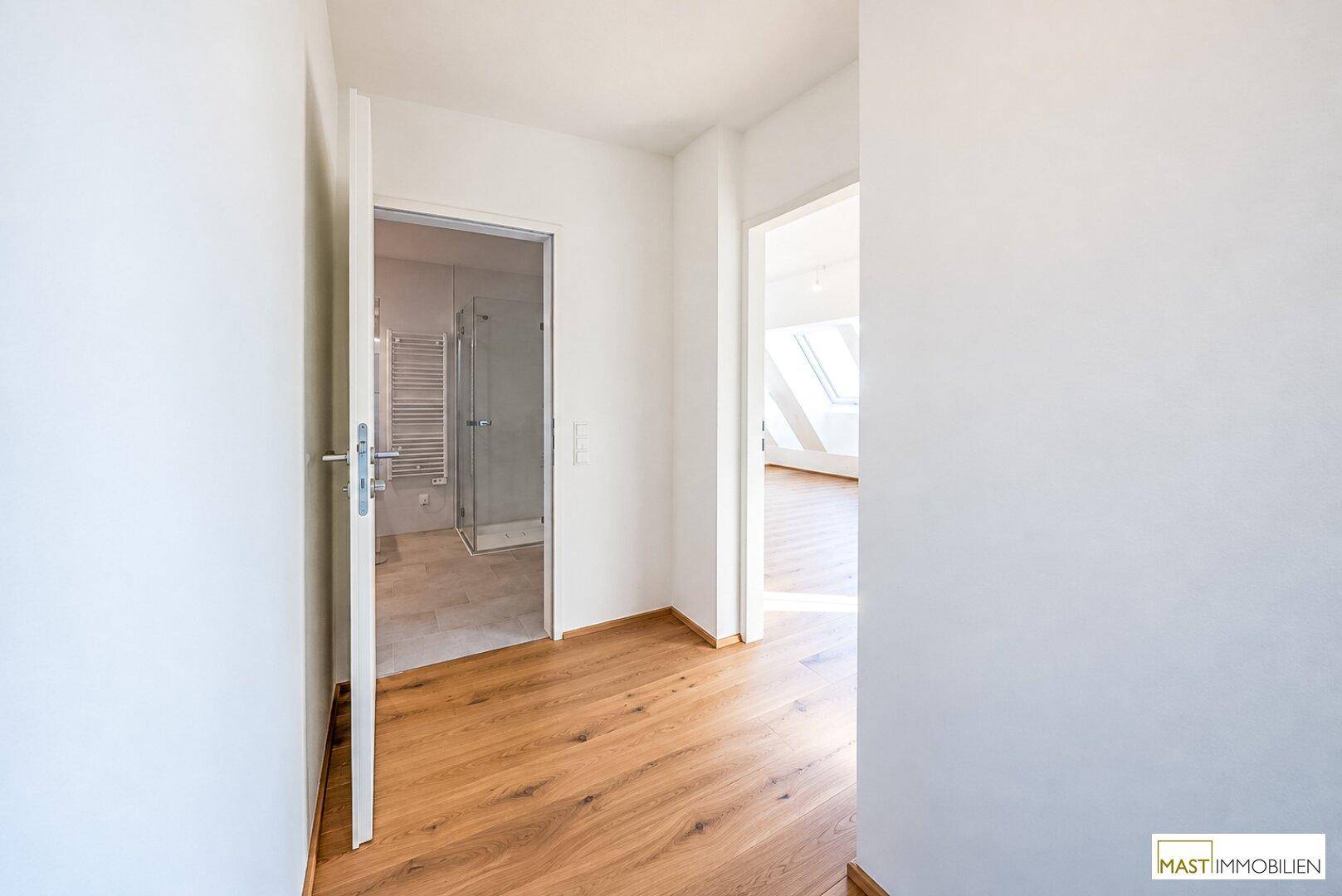 Flur mit Holzboden, der den Zugang zu einem Badezimmer und einem weiteren Raum ermöglicht.