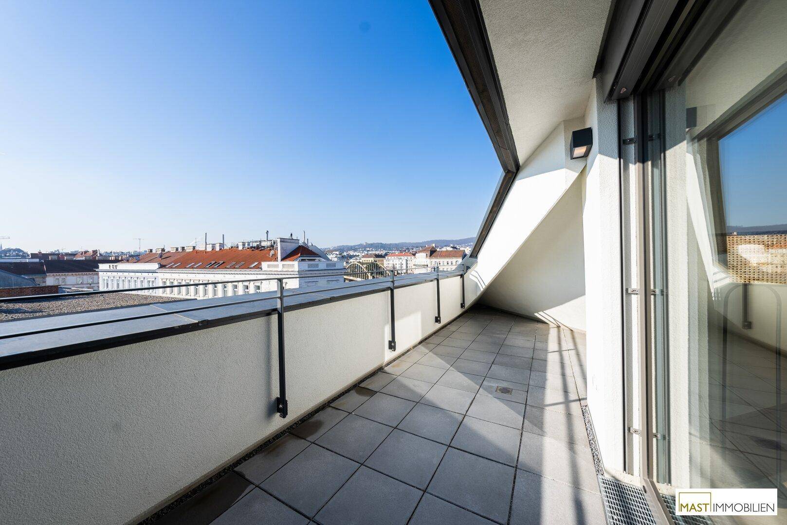 Breite Dachterrasse mit Fliesenboden und weitem Blick über die Stadt, bietet viel Platz.