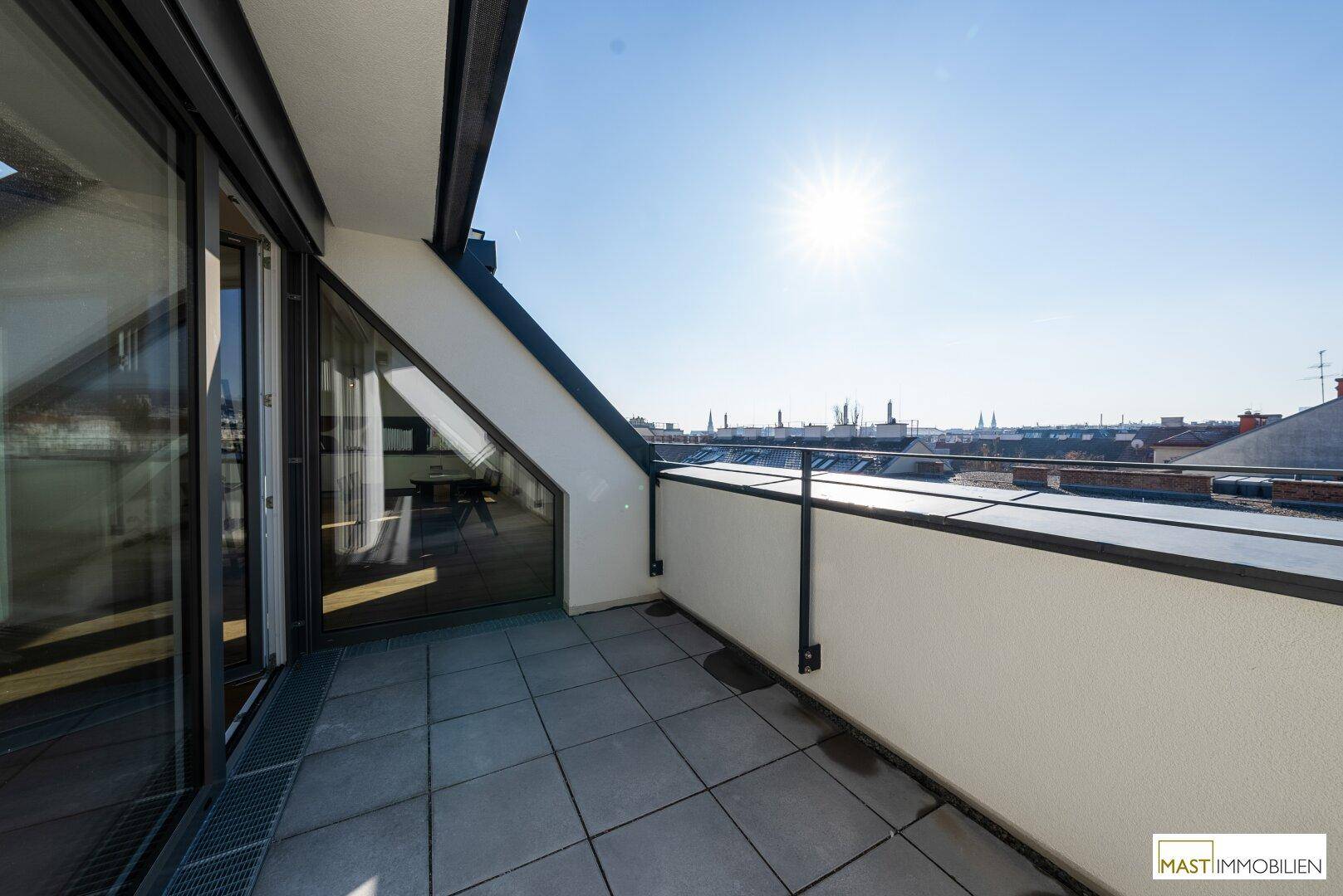 Sonnige Dachterrasse mit Blick auf die Stadt und umliegende Gebäude, ideal für Outdoor-Aktivitäten.