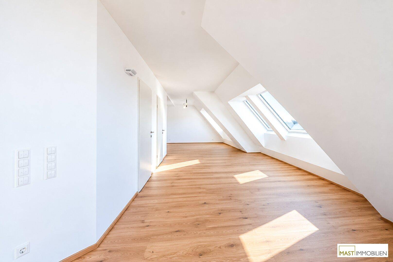 Helles Zimmer im Dachgeschoss mit Holzboden und Dachfenstern, ideal als Schlaf- oder Arbeitszimmer.