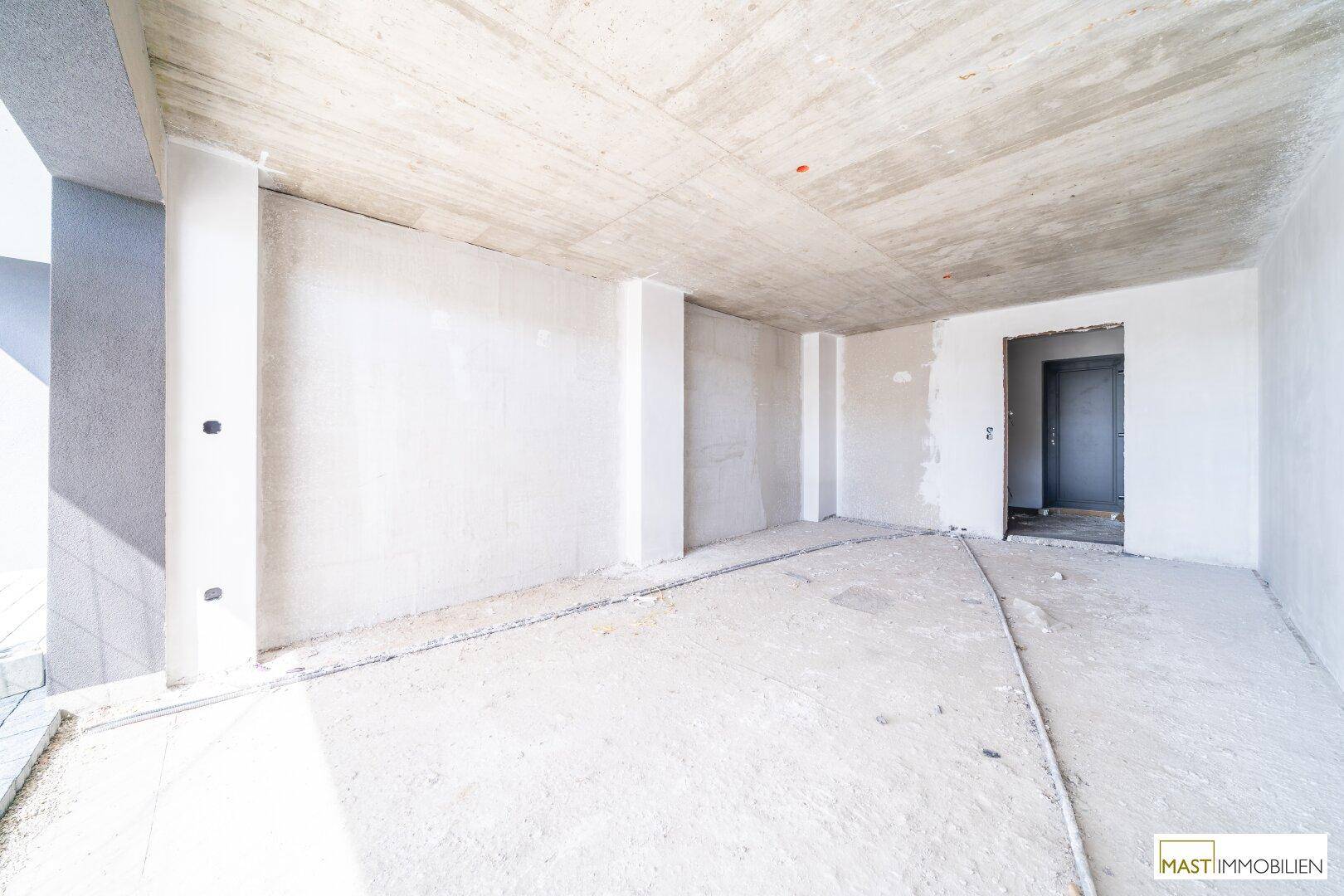 Unfertiger Kellerraum mit Beton-Decke und Zugangstür, ideal als Abstellraum.