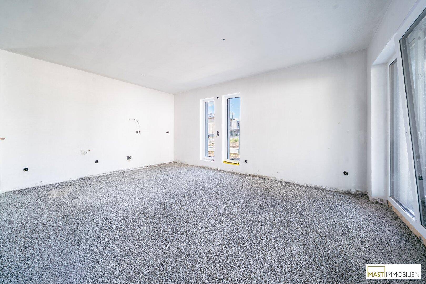 Heller, unfertiger Raum mit großen Fenstern, bereit für den Innenausbau im Neubau.