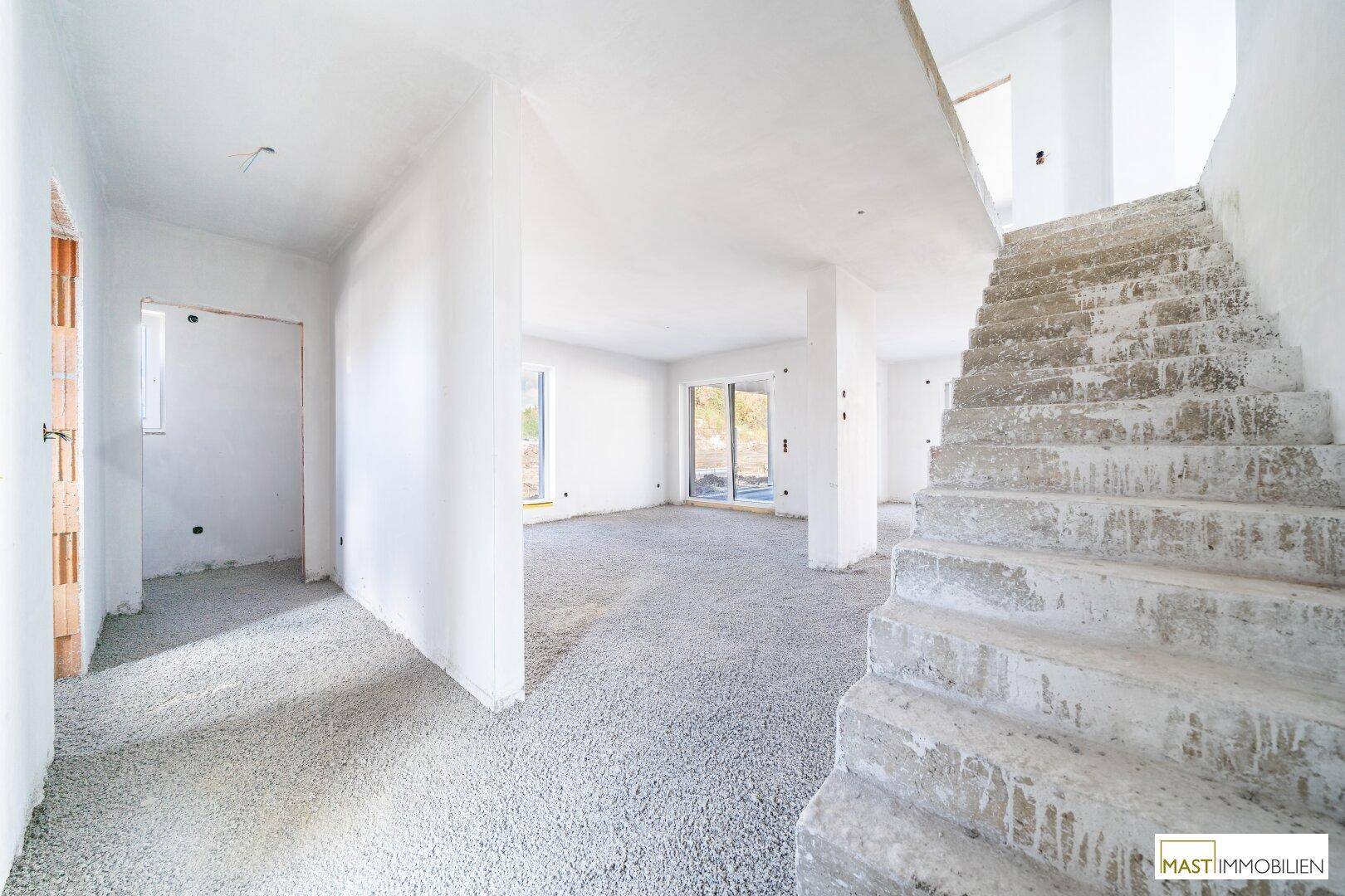 Unfertiger Eingangsbereich mit Rohbau-Treppe und Zugang zu weiteren Räumen.
