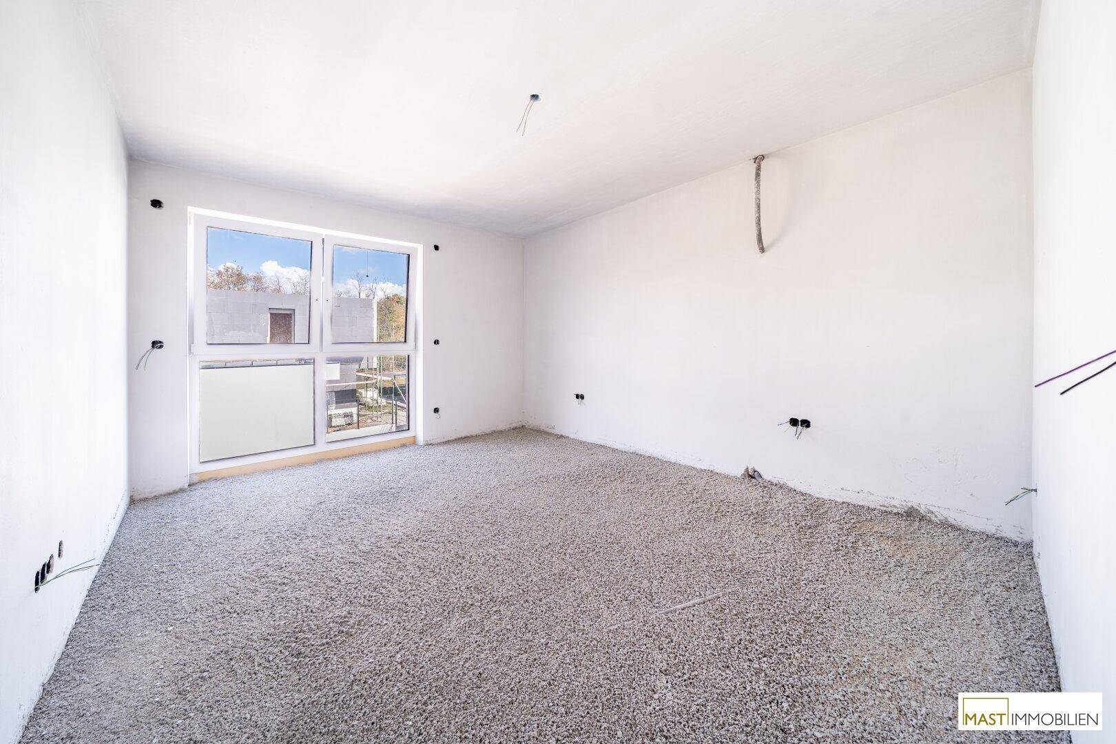 Geräumiges, unfertiges Schlafzimmer mit großem Fenster und Zugang zum Außenbereich.