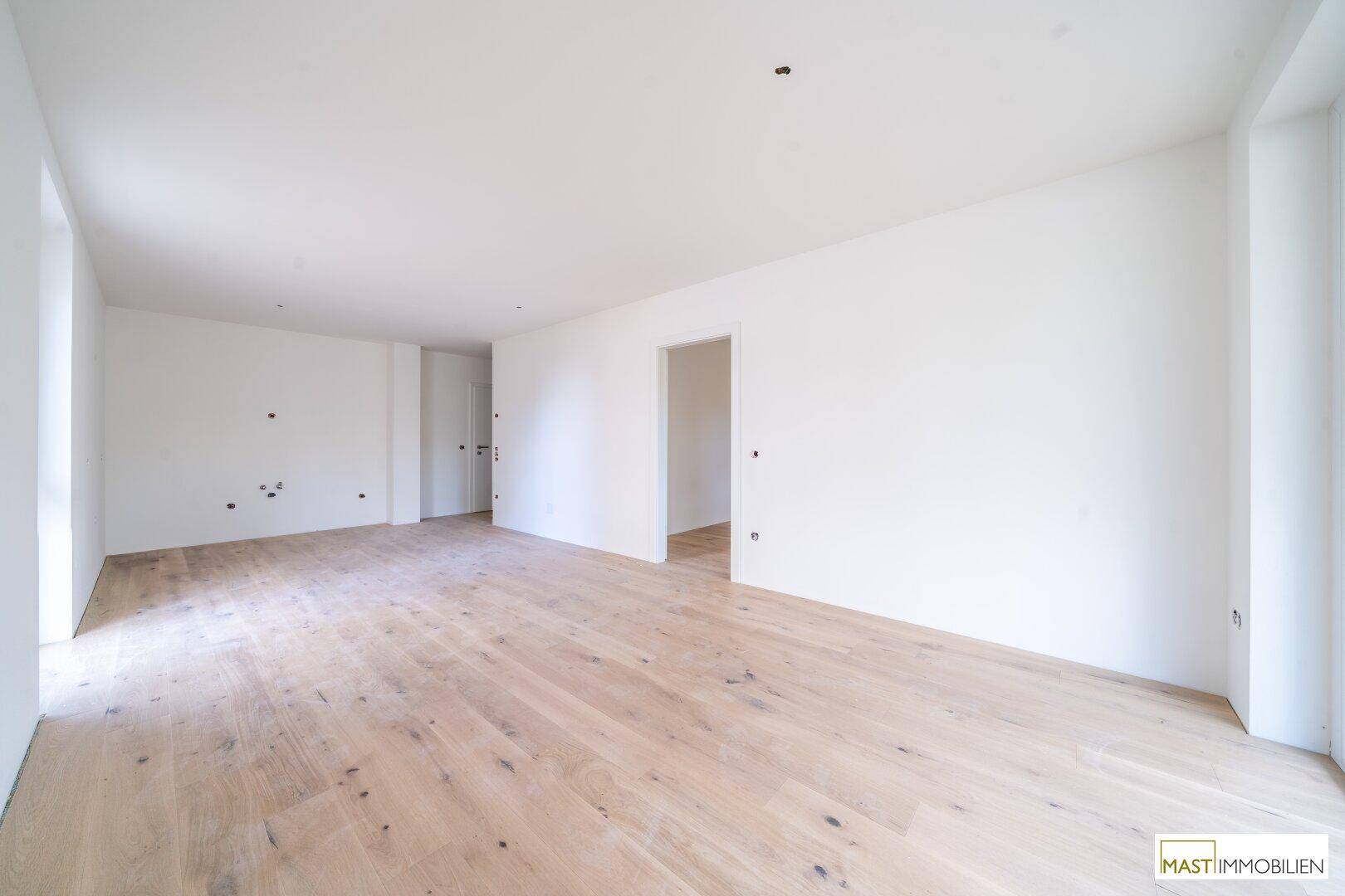 Geräumiges, helles Zimmer mit neuem Holzboden, ideal für Wohn- oder Essbereich.