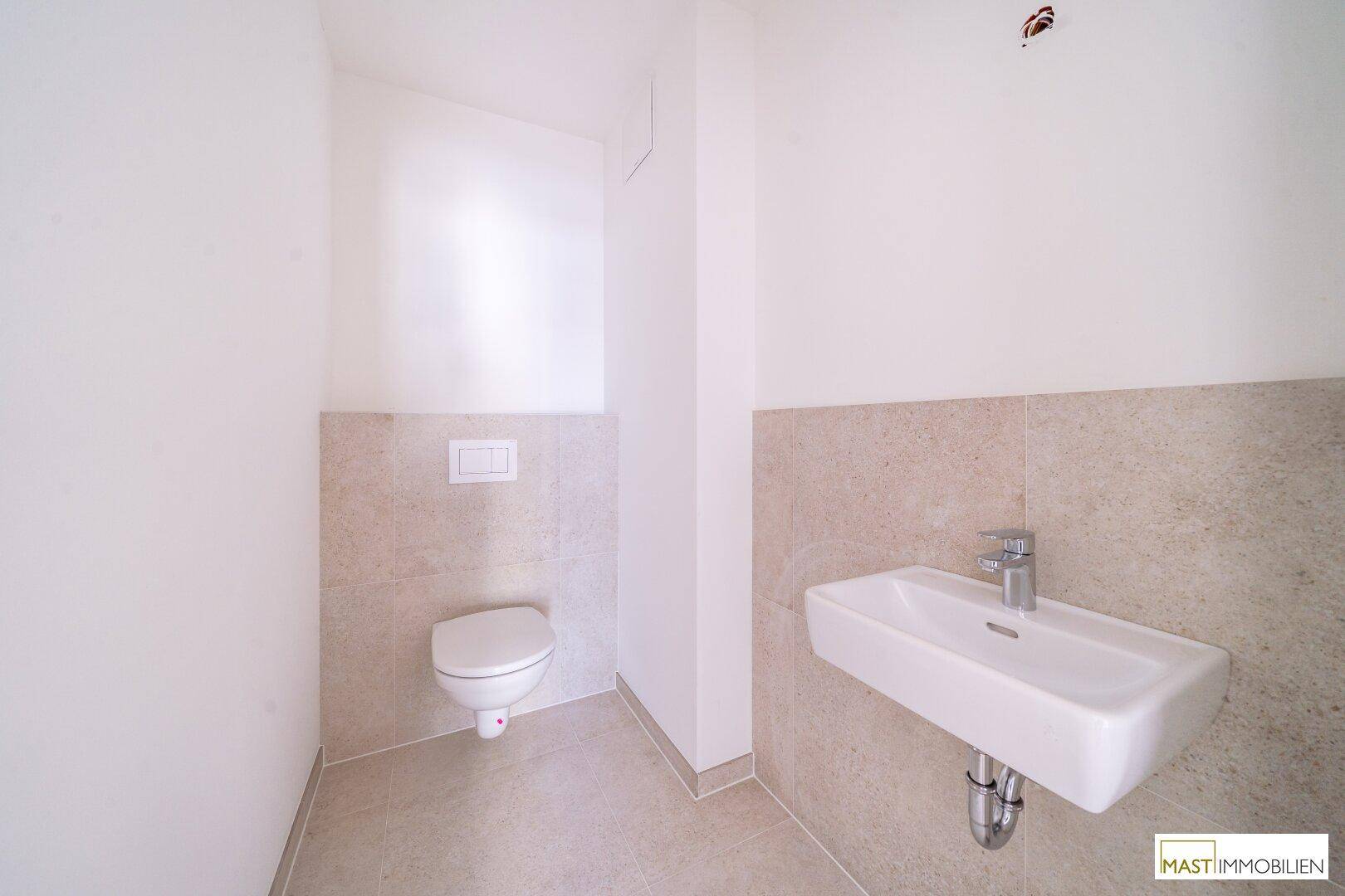 Modernes Gäste-WC mit wandhängender Toilette und kleinem Waschbecken, hell gefliest.
