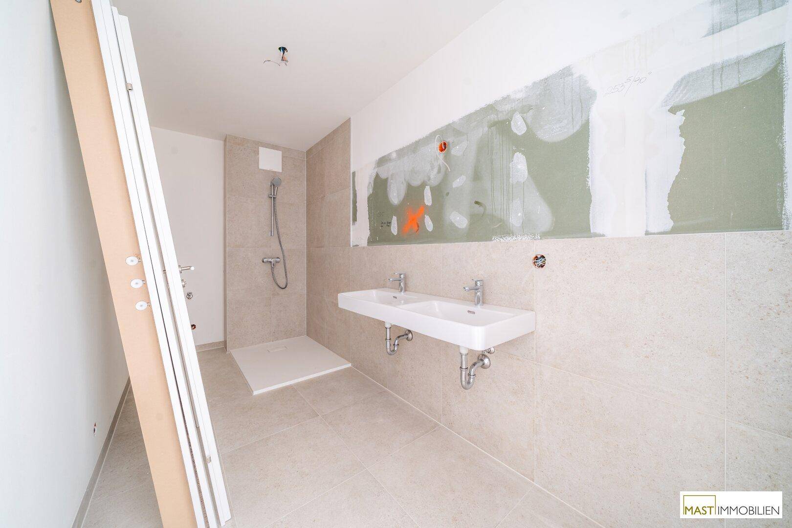 Geräumiges Badezimmer im Bau mit begehbarer Dusche und Doppelwaschbecken, modern gefliest.