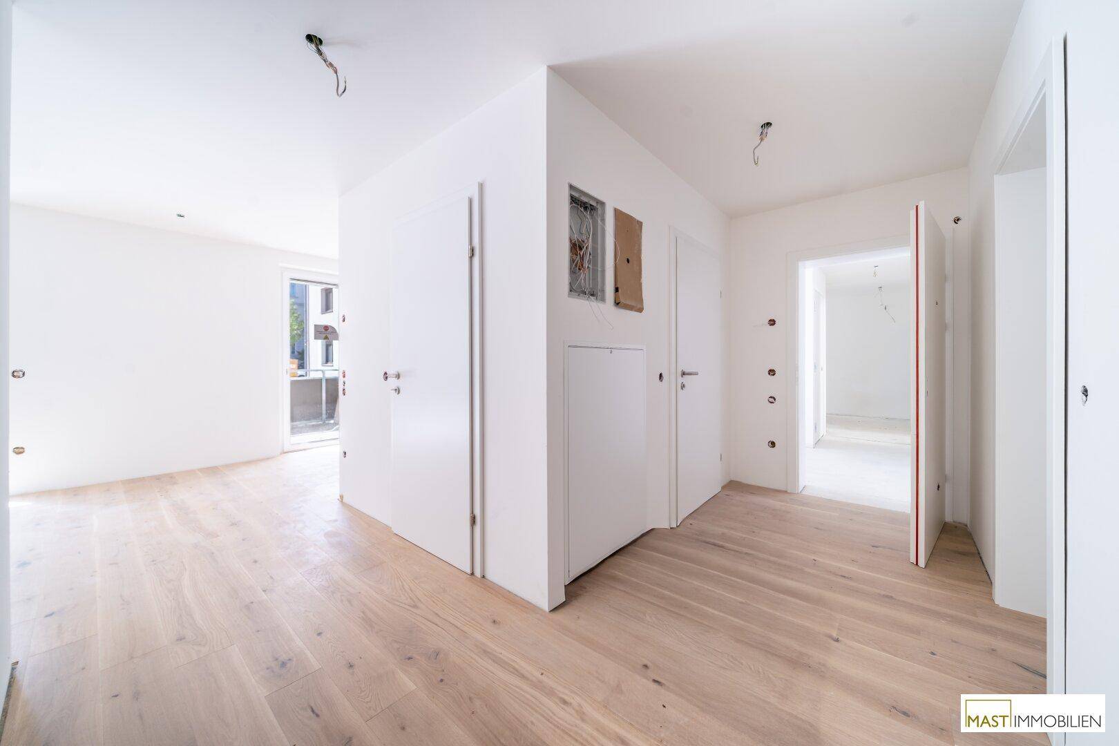 Geräumiger Flur mit Holzboden und mehreren Türen, der verschiedene Bereiche der Wohnung verbindet.