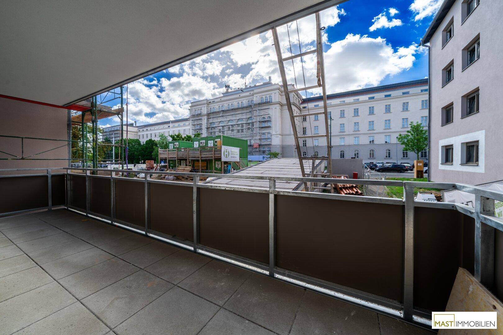 Großer Balkon mit Fliesenboden und Blick auf umliegende Gebäude und Baustellen.