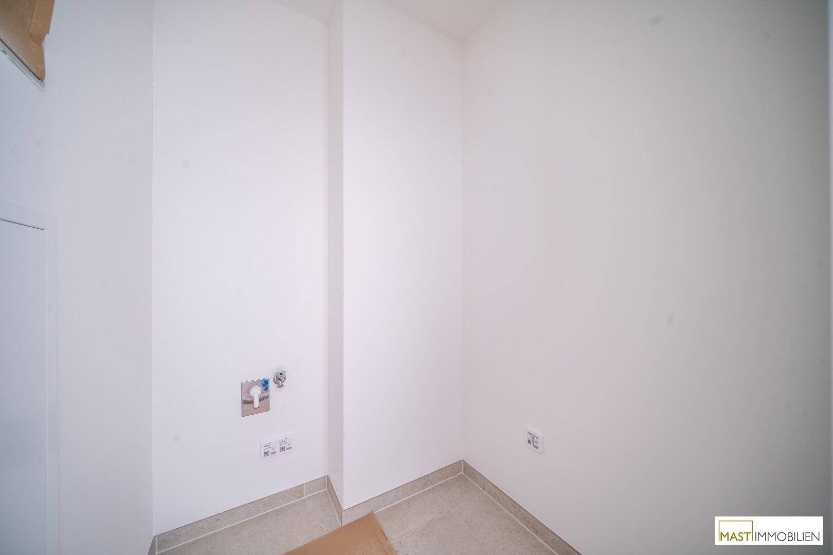 Kleiner Hauswirtschaftsraum mit Fliesenboden und Anschlüssen für Waschmaschine und Trockner.