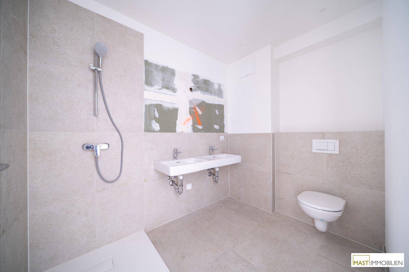 Modernes Badezimmer mit Doppelwaschbecken, Dusche und Wand-WC, teilweise noch im Bau.