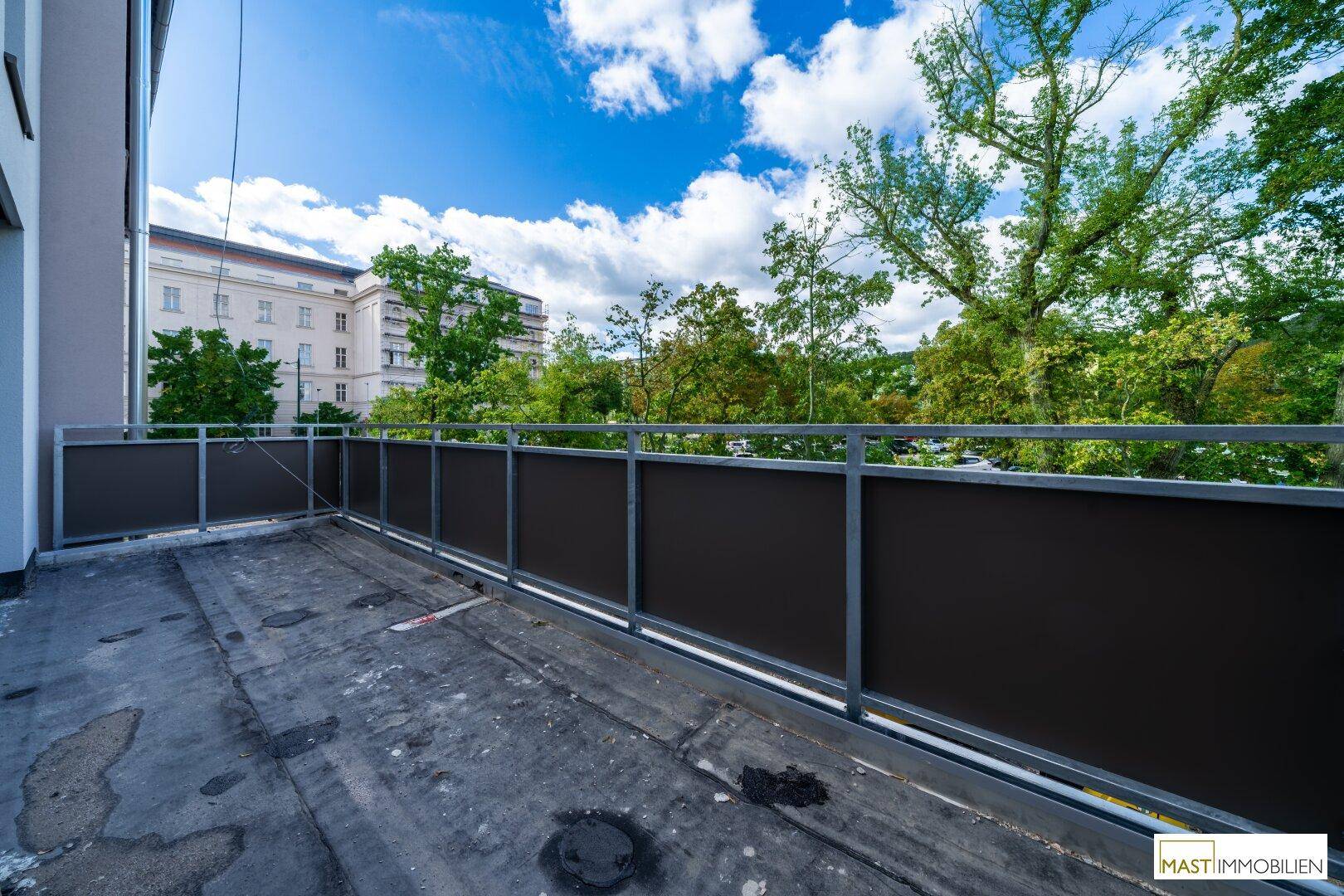 Geräumiger Balkon mit Blick ins Grüne und auf umliegende Gebäude, ideal zum Entspannen.