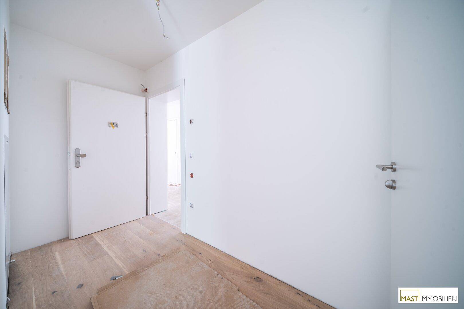 Heller Flur mit Holzboden und mehreren Türen zu angrenzenden Räumen.
