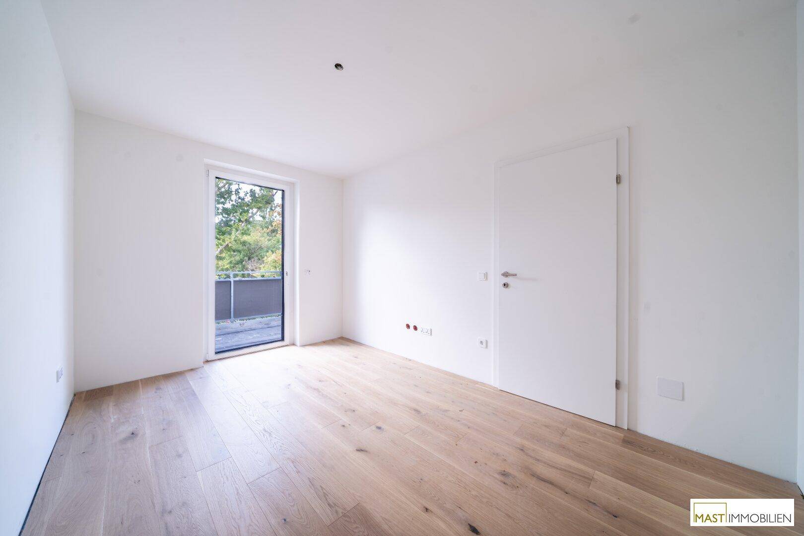 Schlafzimmer mit hellem Holzboden und direktem Zugang zu einem Außenbereich.