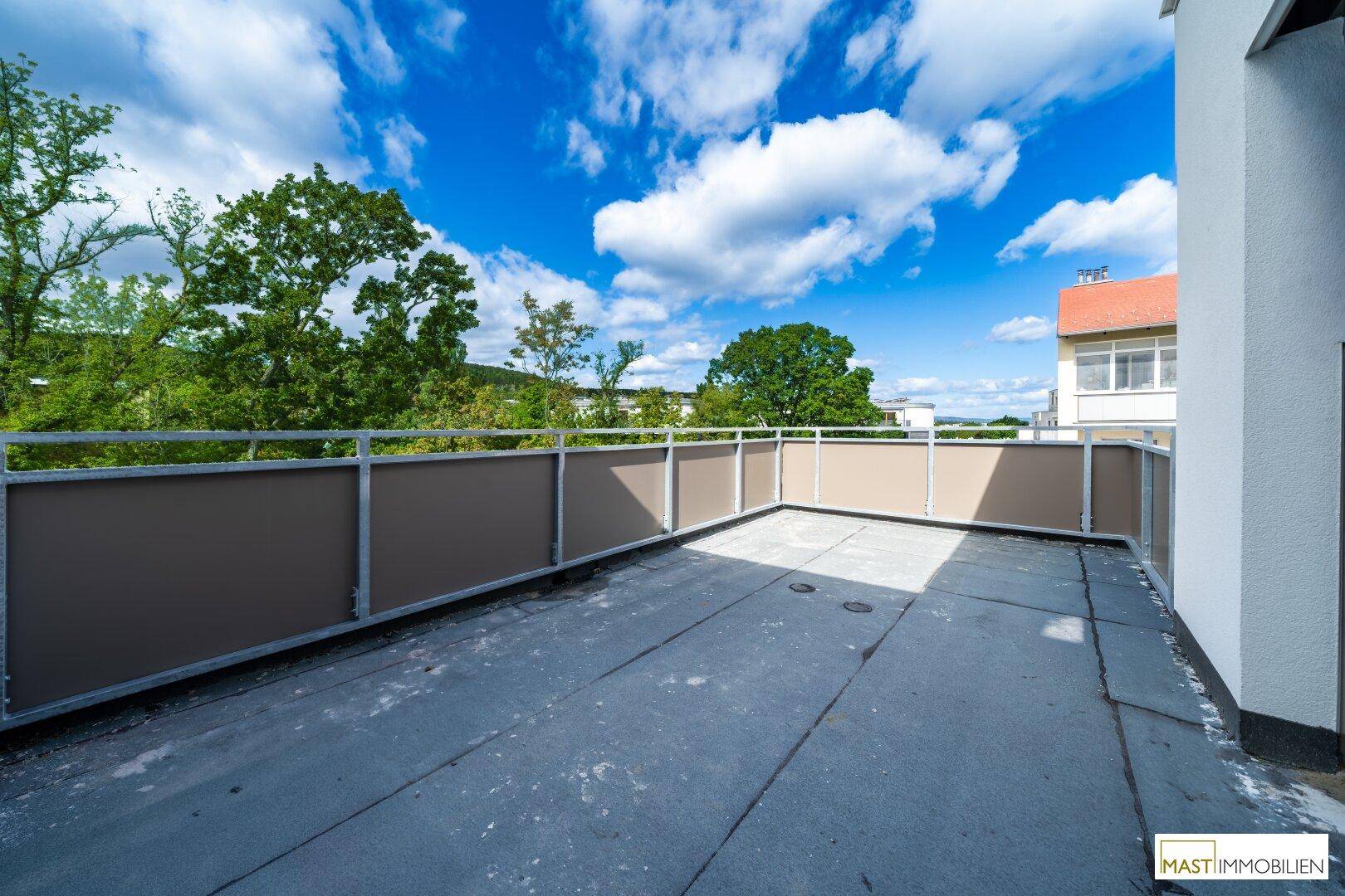 Große, unmöblierte Dachterrasse mit weitem Blick und blauem Himmel, ideal für Entspannung.