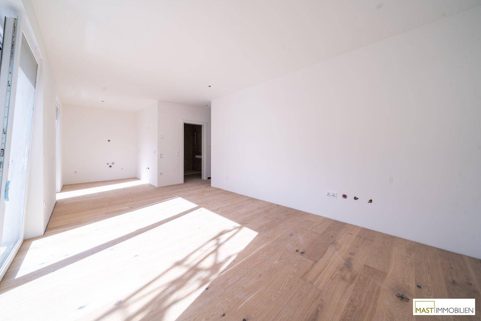 Geräumiger, heller Raum mit neuem Holzboden und weißen Wänden, bereit zum Einzug.