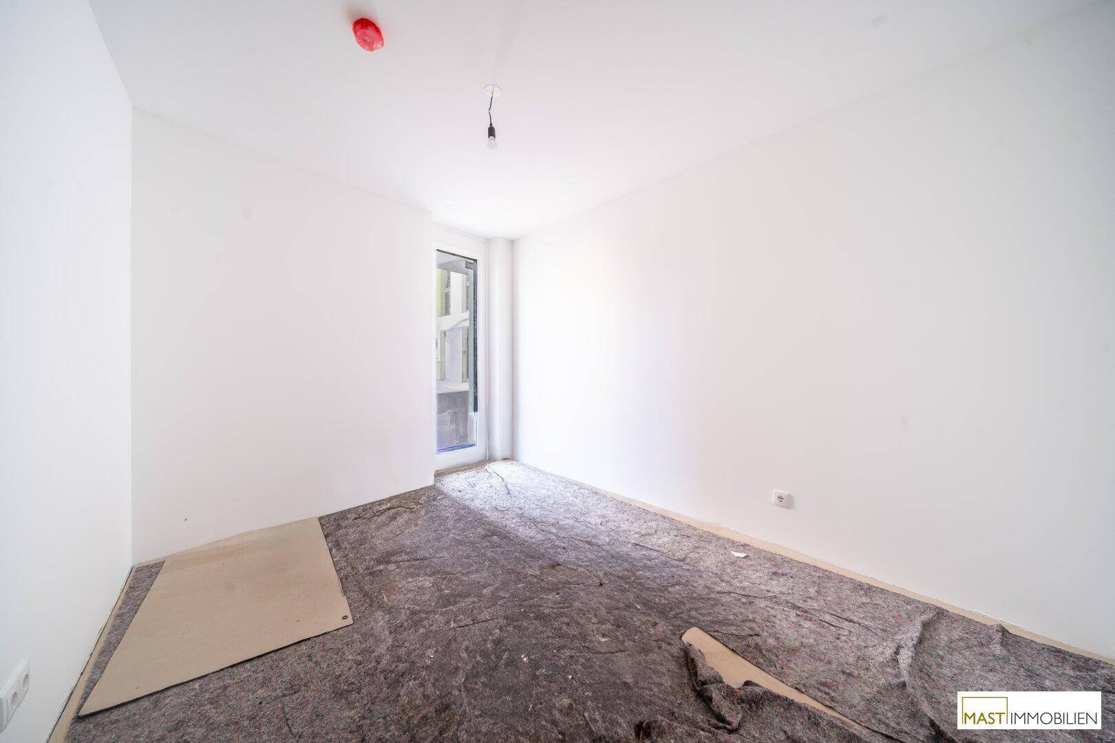 Unmöbliertes Zimmer mit weiß gestrichenen Wänden und geschütztem Boden, bereit für die Endbearbeitung.