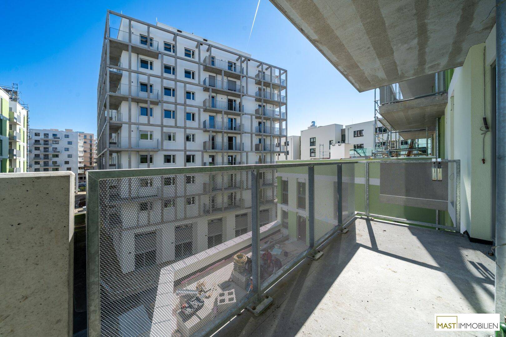 Balkon mit Metallgeländer und weitem Blick auf die moderne Architektur der umliegenden Gebäude.