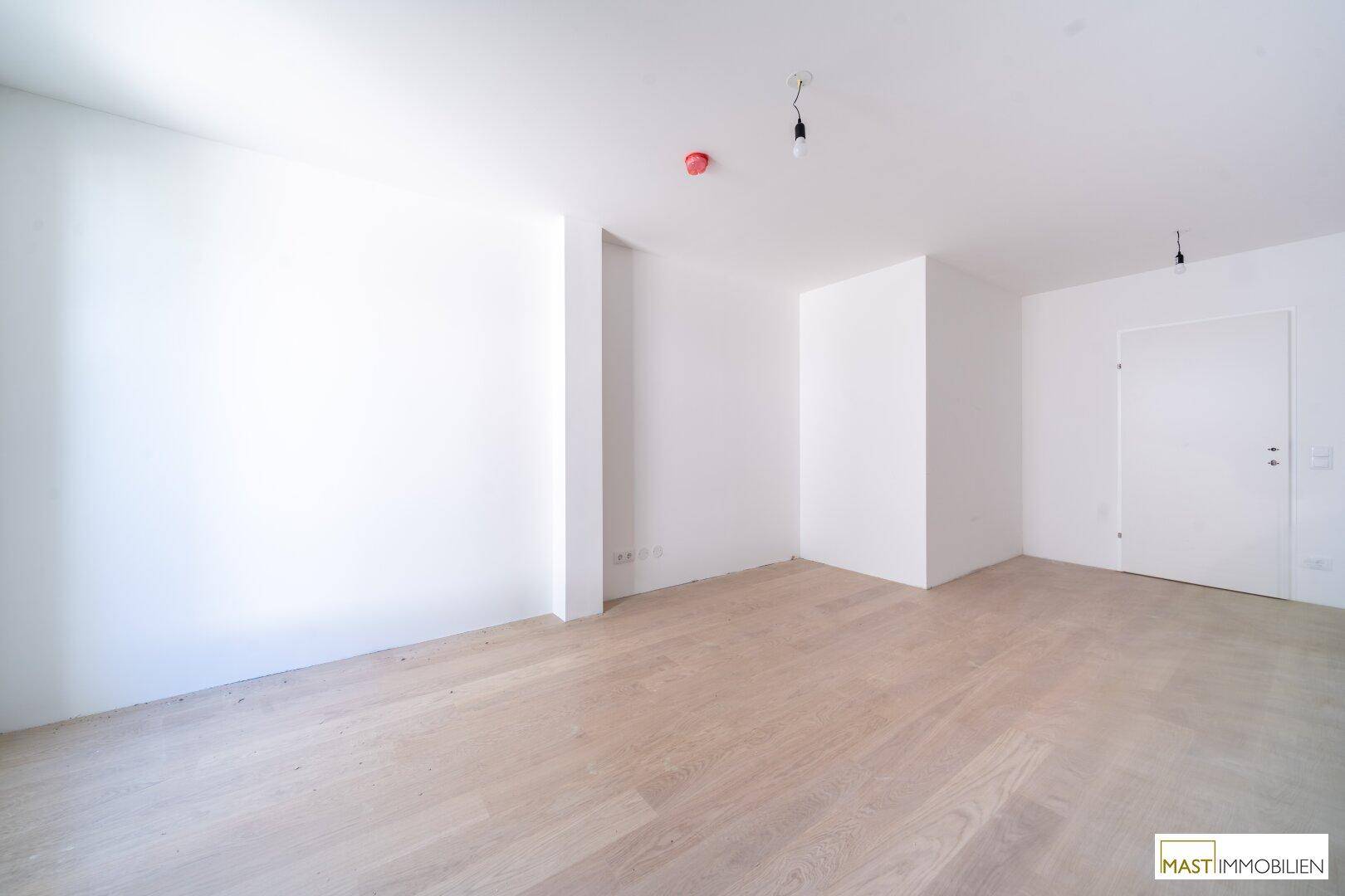 Leeres Zimmer mit hellen Wänden und Parkettboden, ideal als Schlaf- oder Arbeitszimmer.