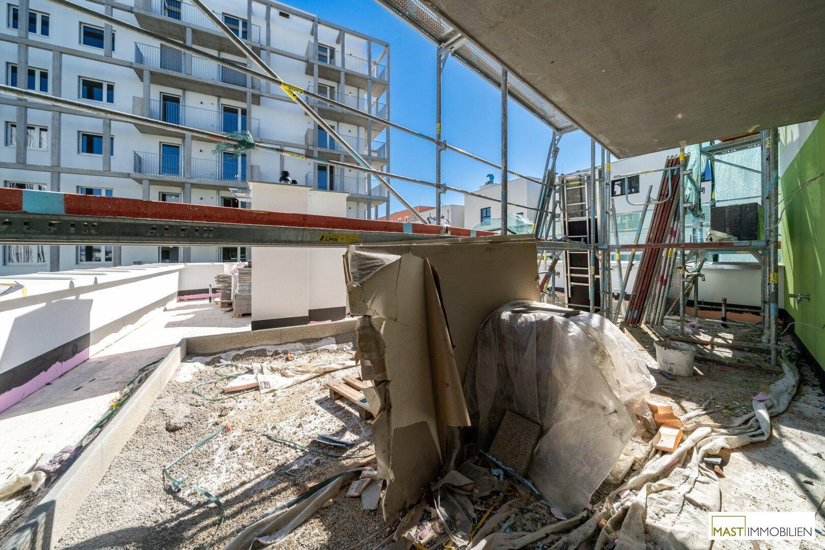 Baustelle des Gebäudes mit Gerüst und Baumaterialien, zeigt den Fortschritt des Neubaus.