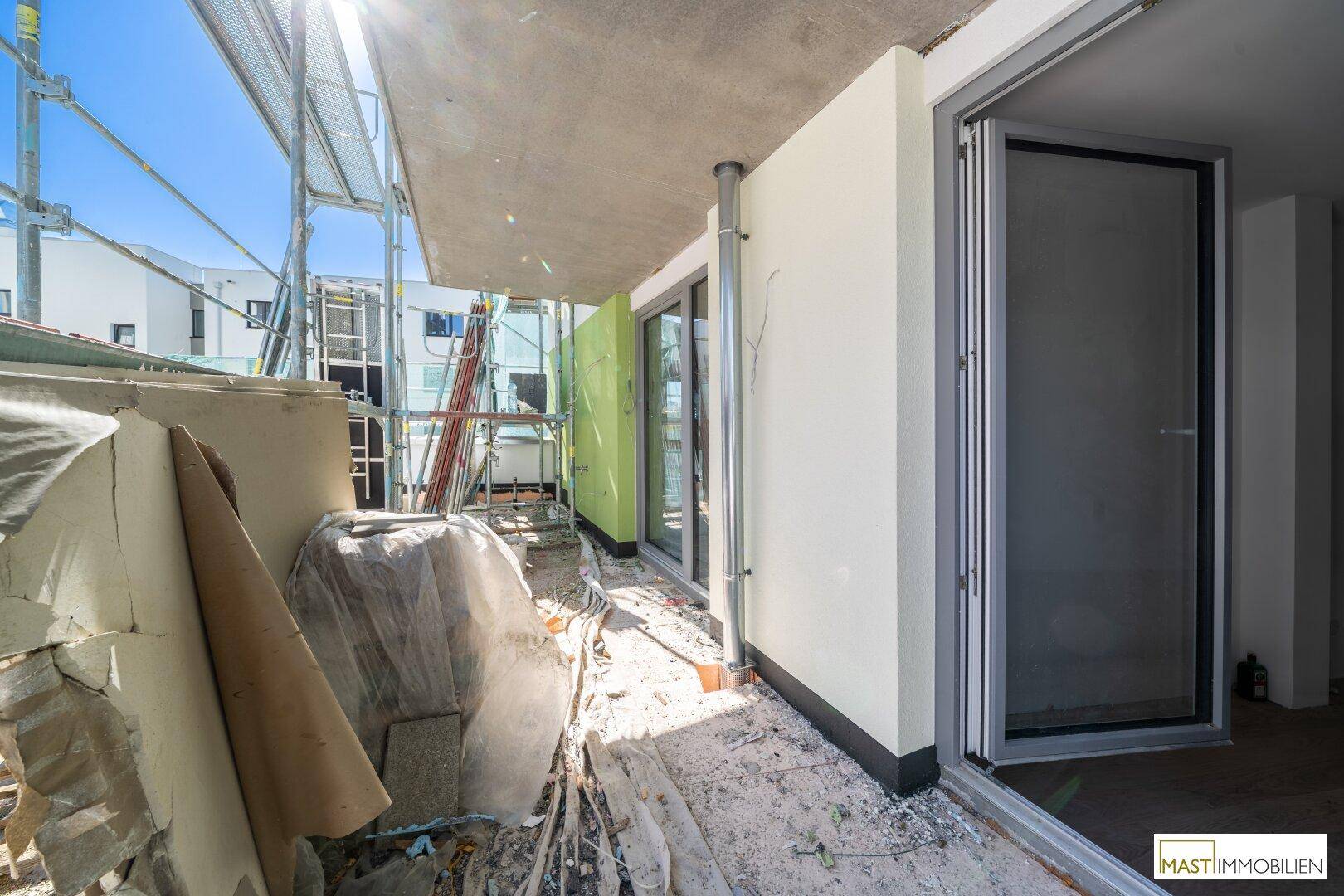 Loggia im Bau mit Gerüst und Baumaterialien, zeigt den Zustand der Außenbereiche.
