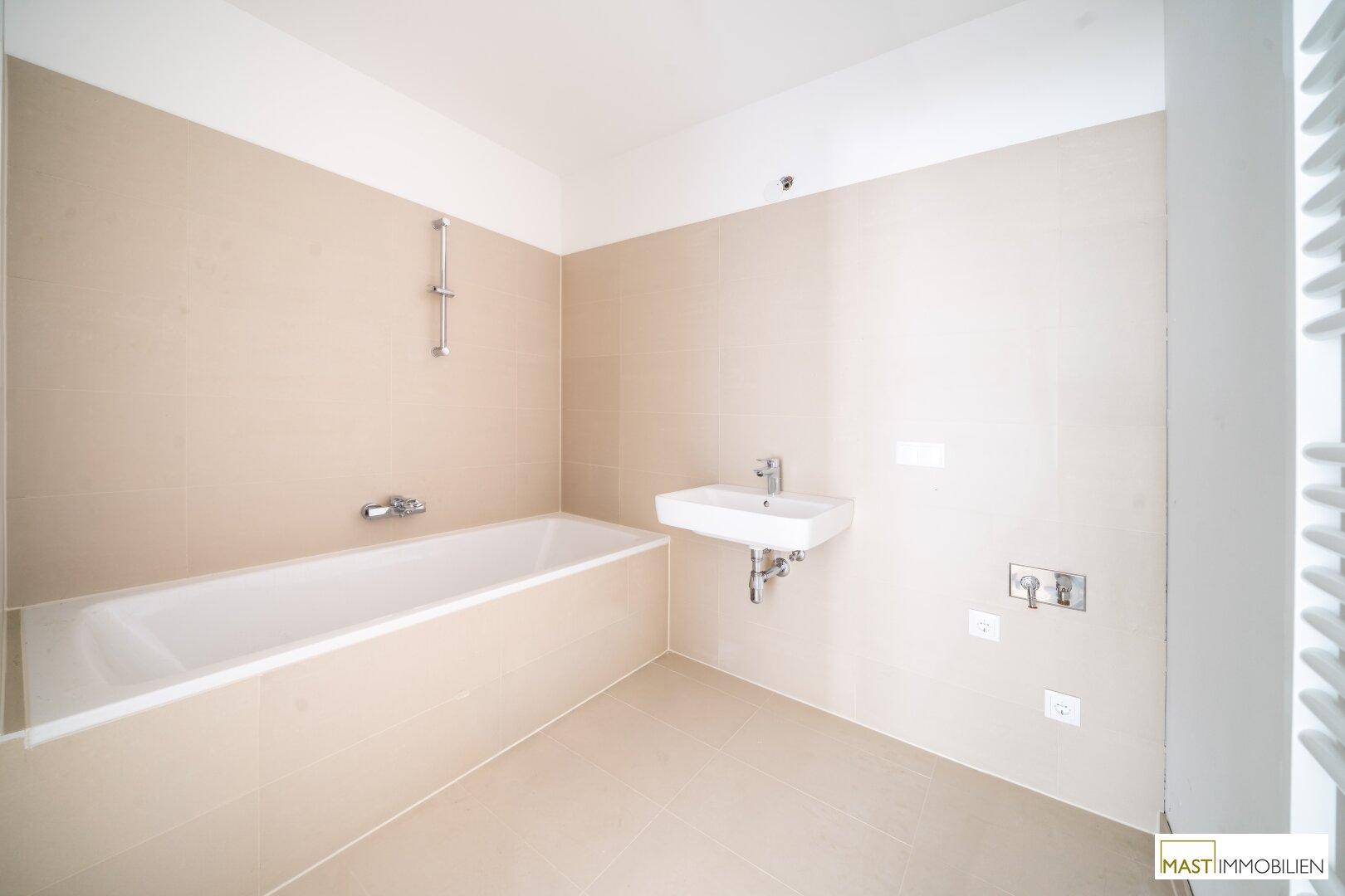 Modernes Badezimmer mit Badewanne, Einzelwaschbecken und beigefarbenen Fliesen.
