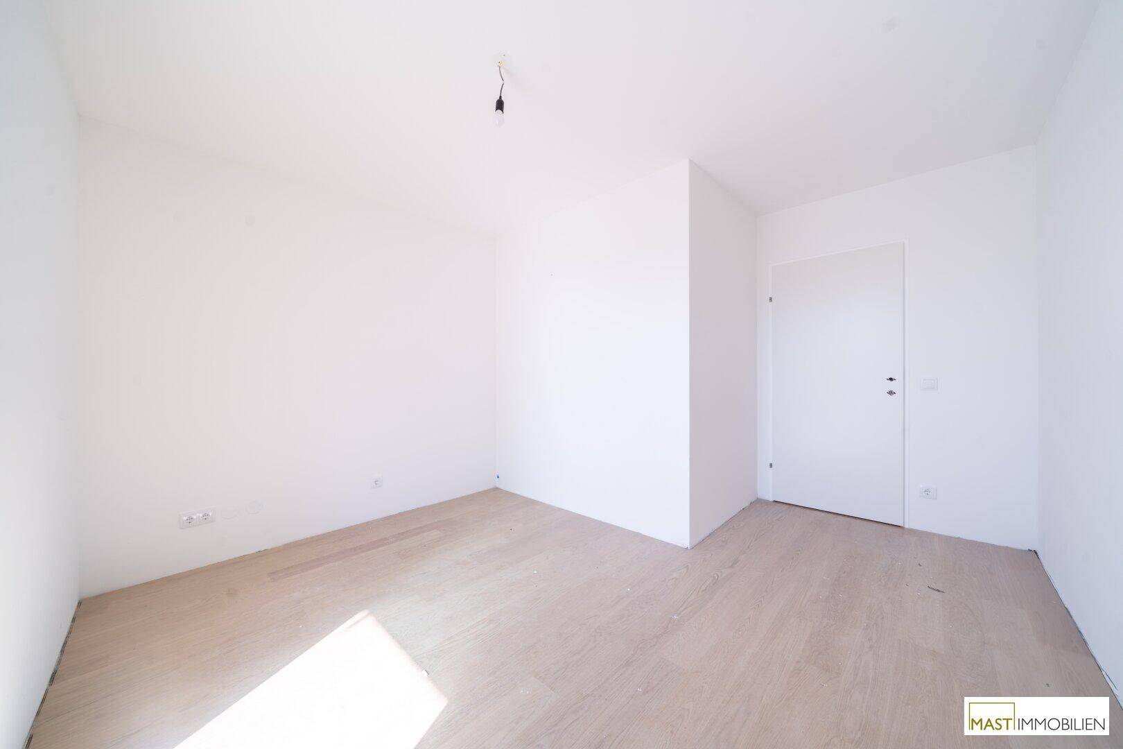 Unmöbliertes Zimmer mit weiß gestrichenen Wänden und hellem Parkettboden, bereit zum Einzug.