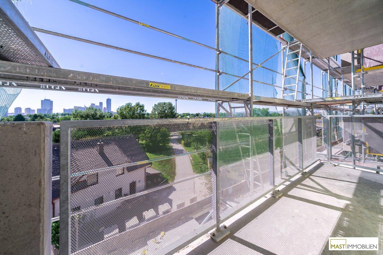 Balkon im Bau mit Gerüst und Fernblick auf die Stadt, bereit für die Fertigstellung.