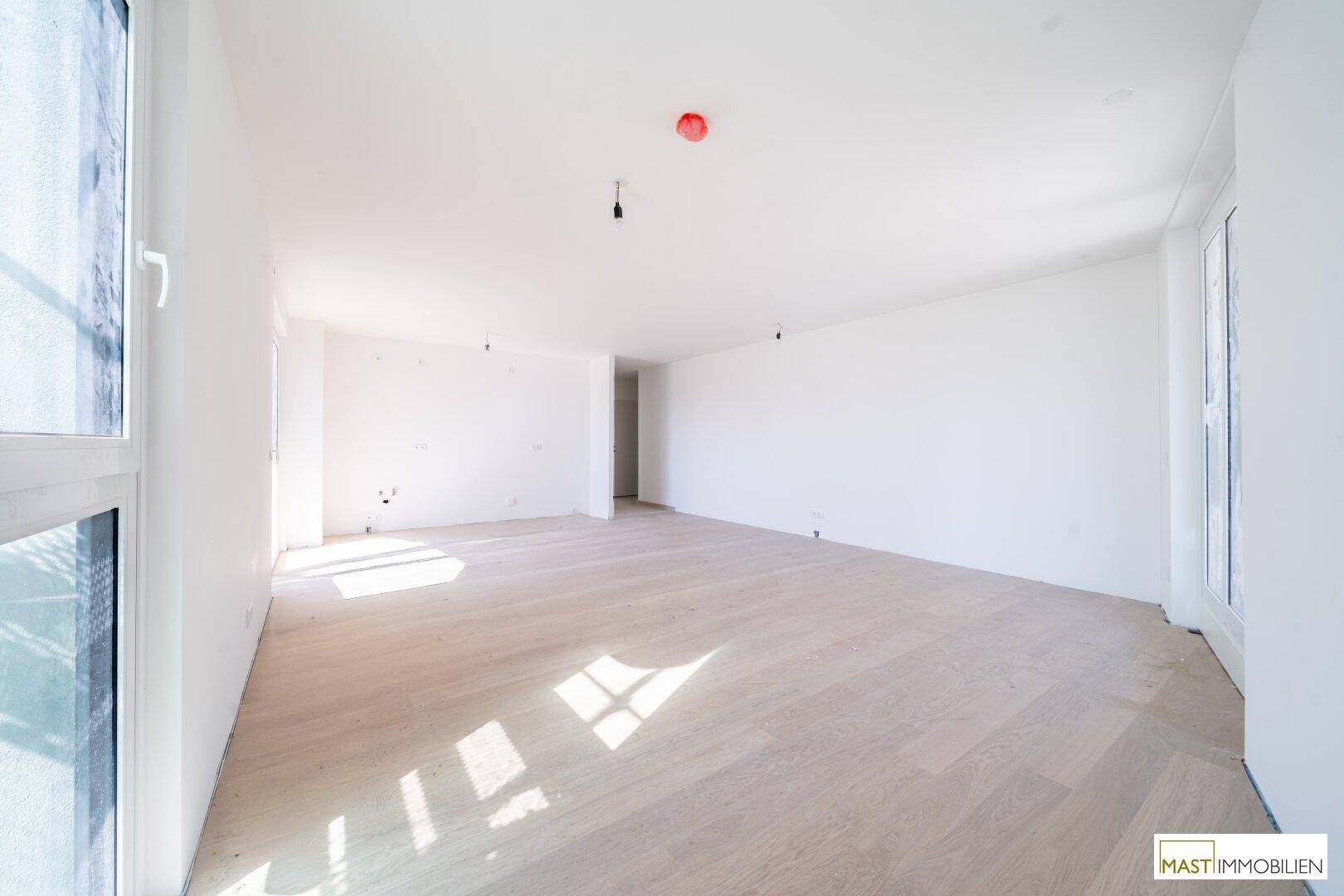 Geräumiges, helles Zimmer mit Parkettboden und viel Tageslicht, ideal für ein Wohnzimmer.