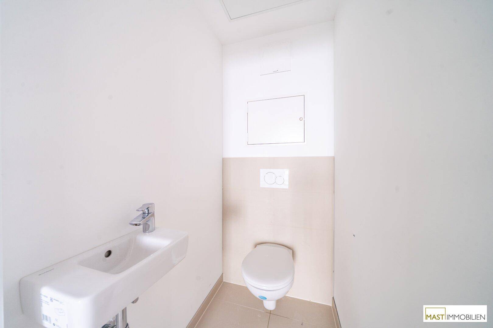 Kleines Gäste-WC mit wandhängender Toilette und kompaktem Waschbecken in hellen Farbtönen.