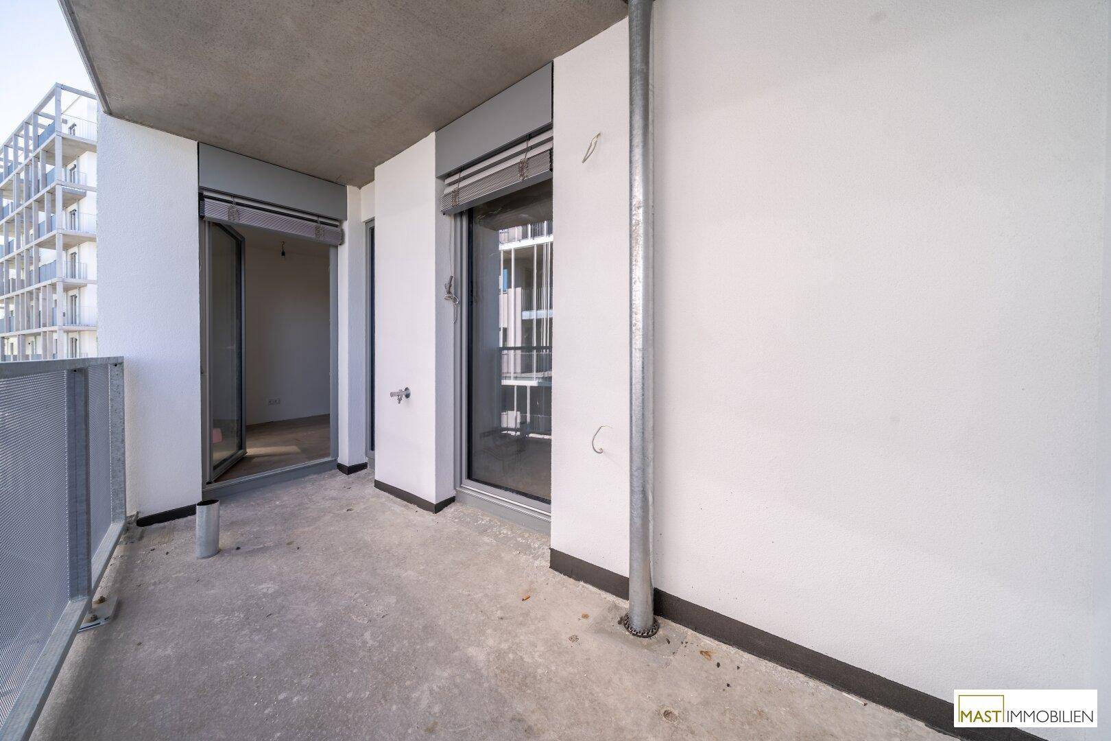 Geräumiger Balkon mit Betonboden und Blick auf die umliegenden modernen Gebäude.