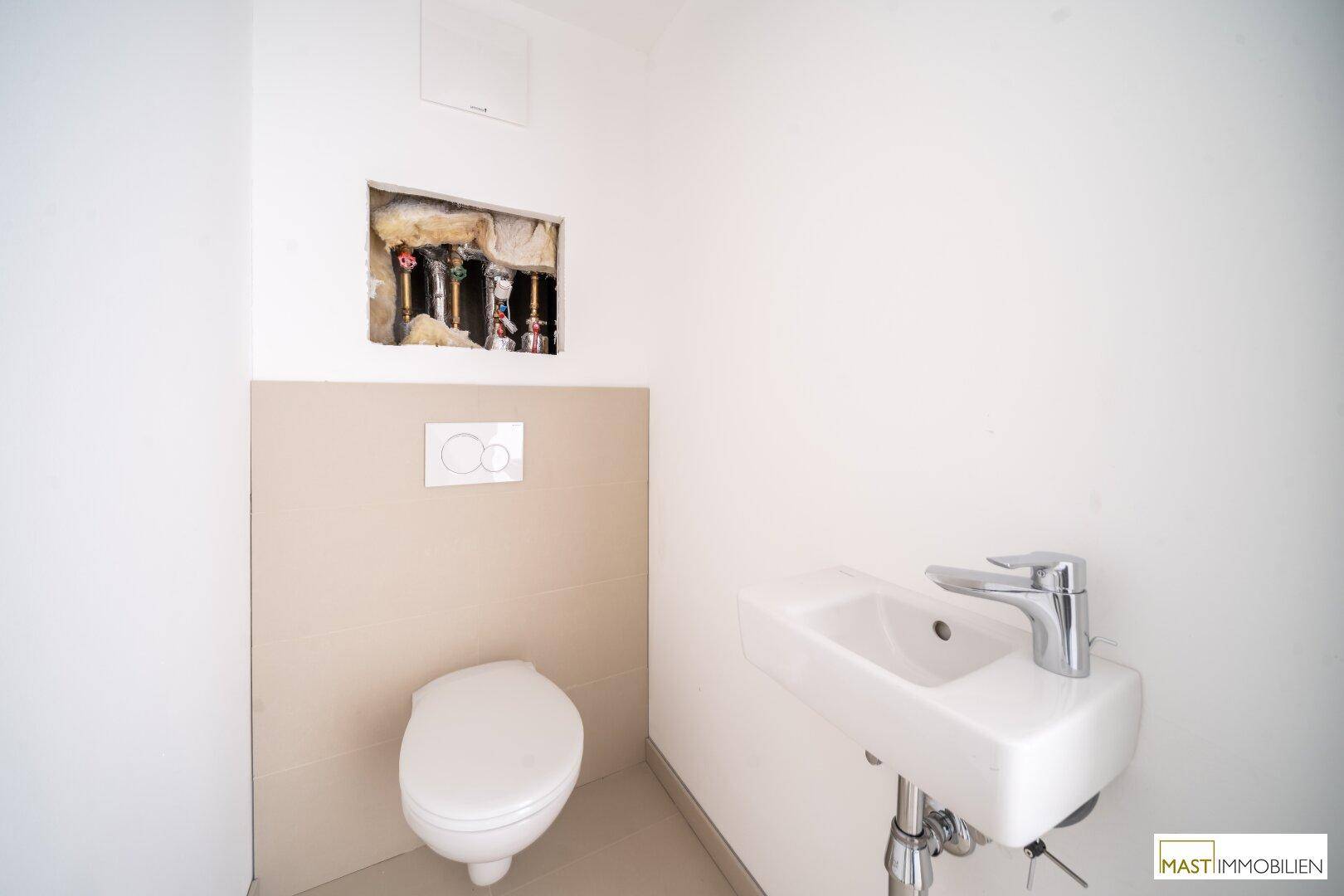Kleine Gästetoilette im Bau mit Wand-WC und Waschbecken.