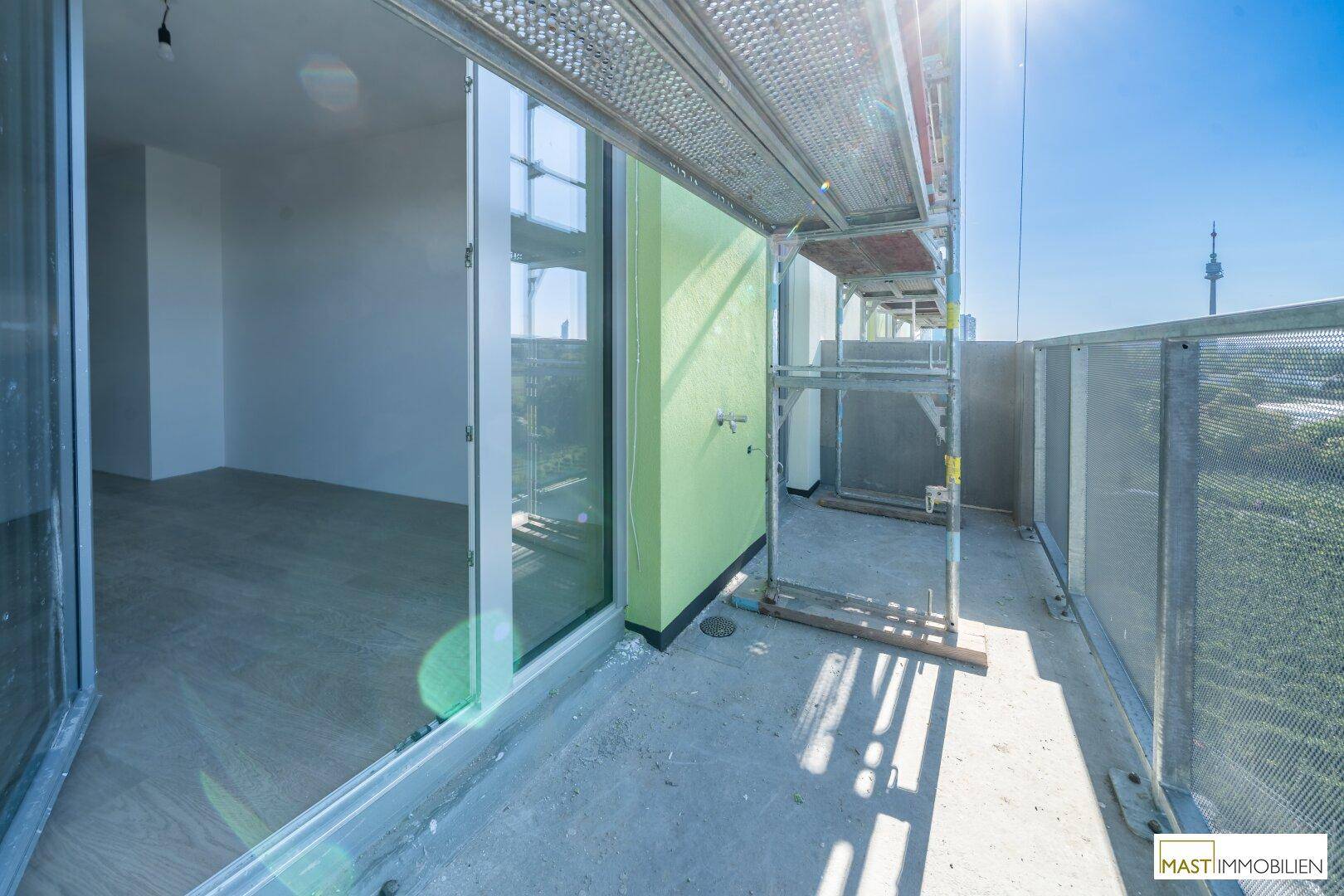 Balkon im Bau mit großen Glasschiebetüren und Blick in den Innenraum.
