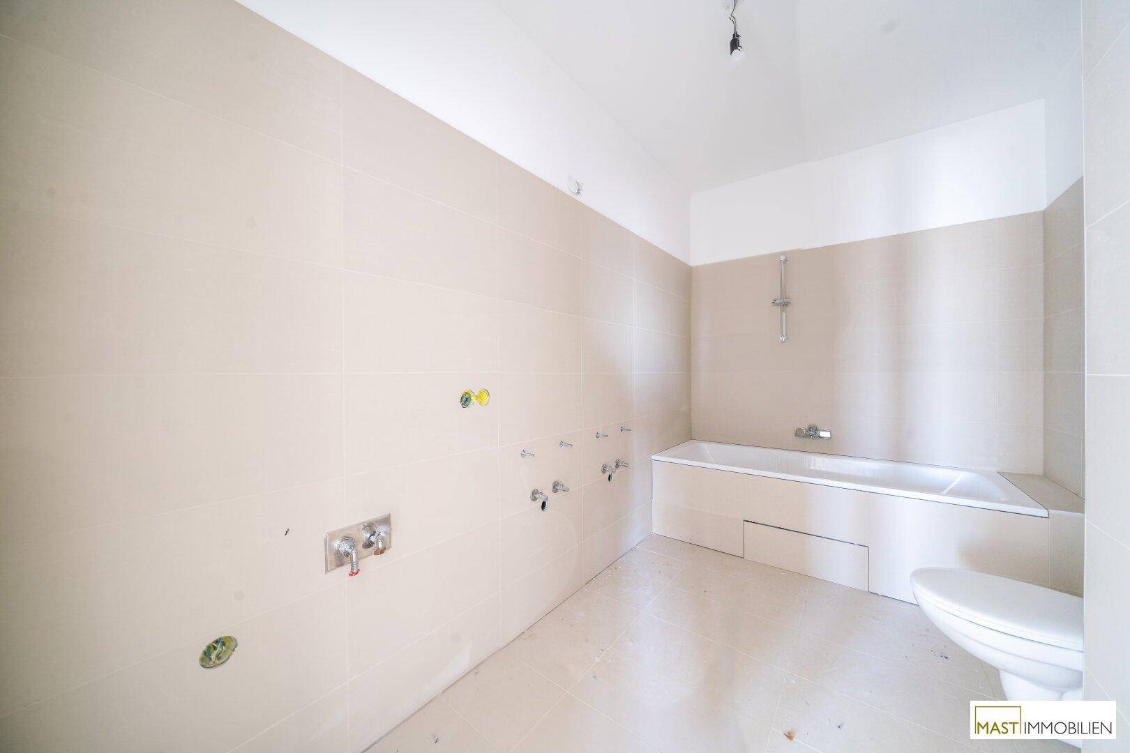 Geräumiges Badezimmer mit beigefarbenen Fliesen, Badewanne und Duschmöglichkeit.