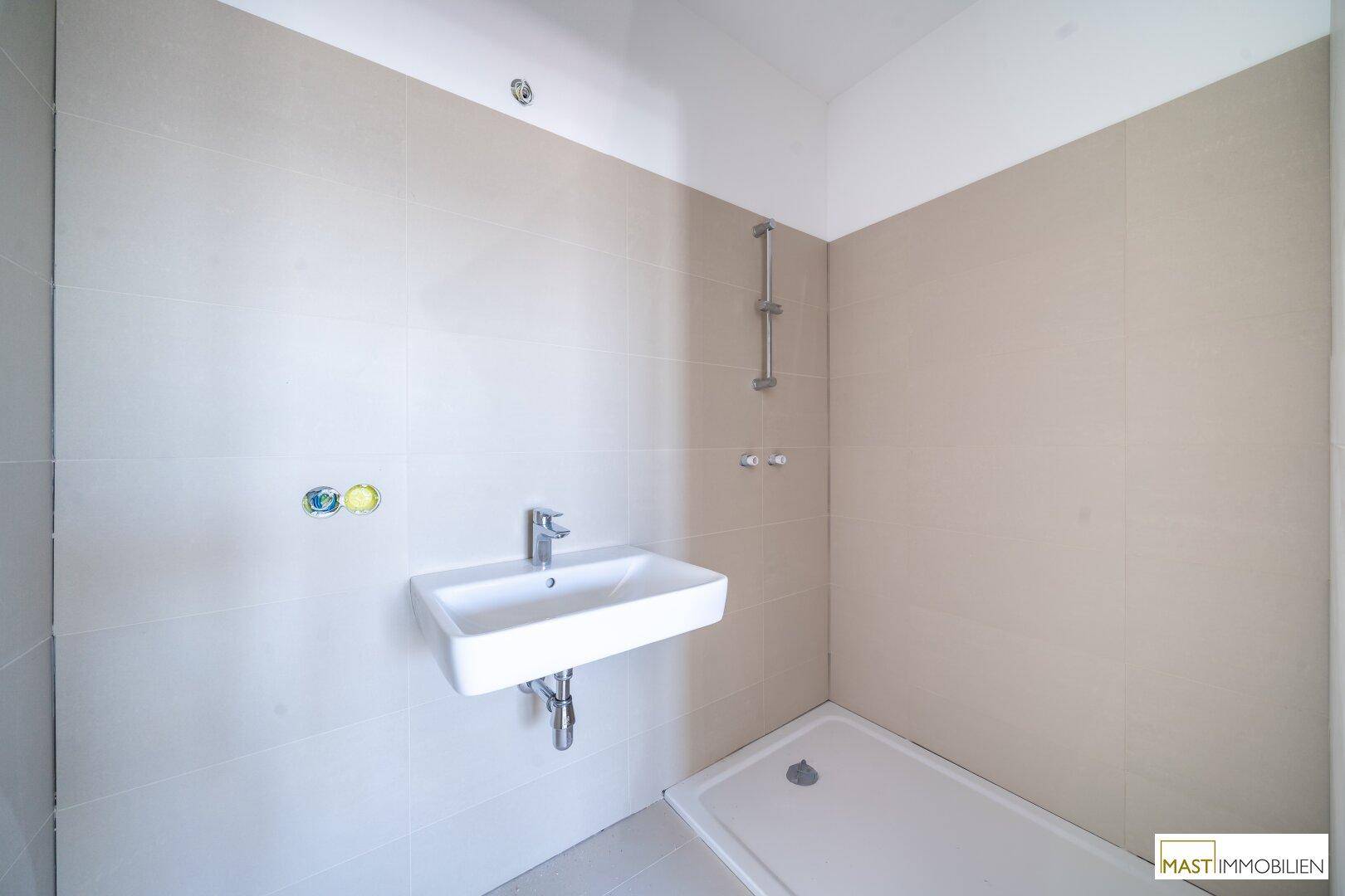 Modernes Badezimmer mit beigefarbenen Fliesen, Waschbecken und einer Duschwanne.