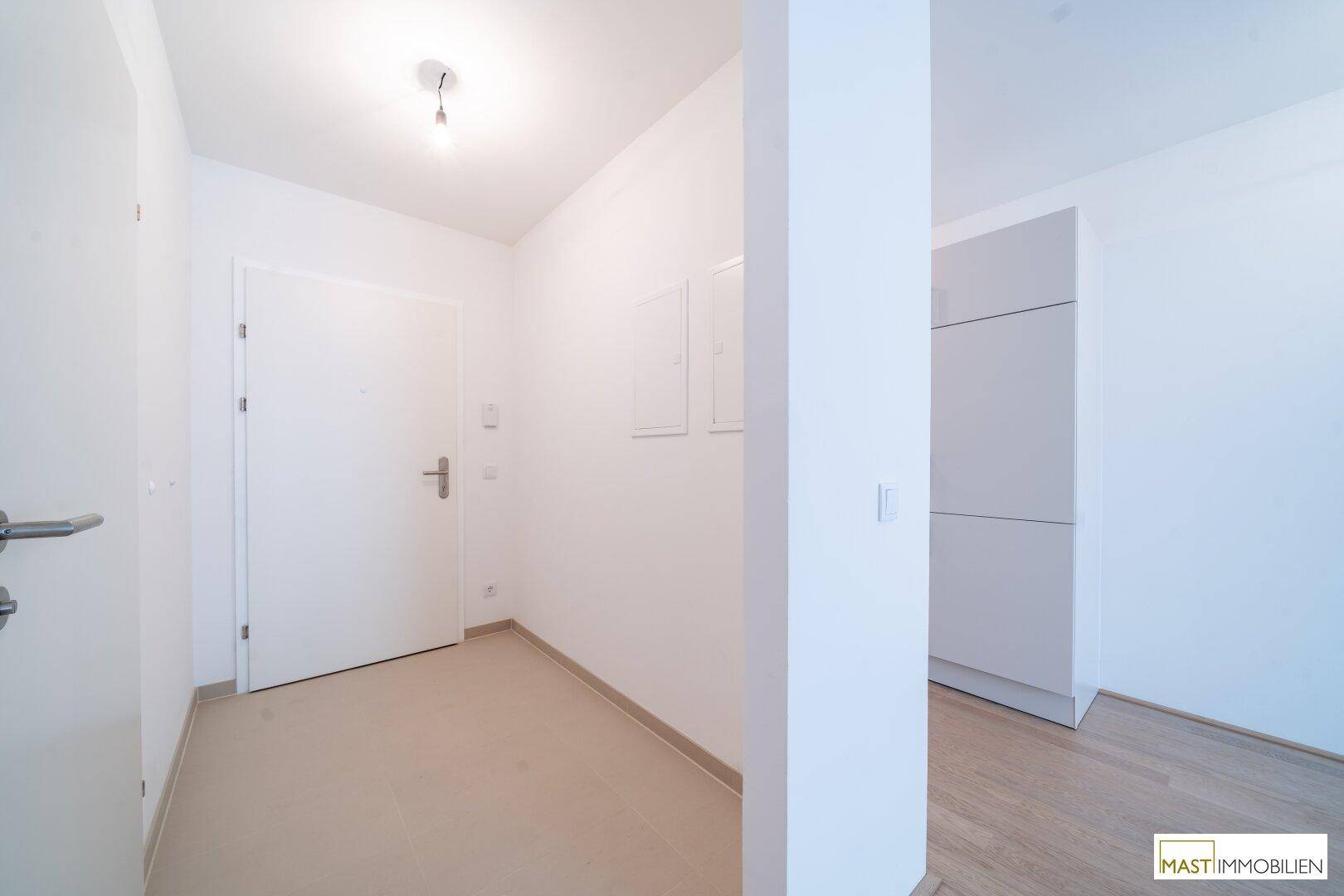 Heller Eingangsbereich mit weißer Tür, Fliesenboden und praktischen, integrierten Einbauschränken.