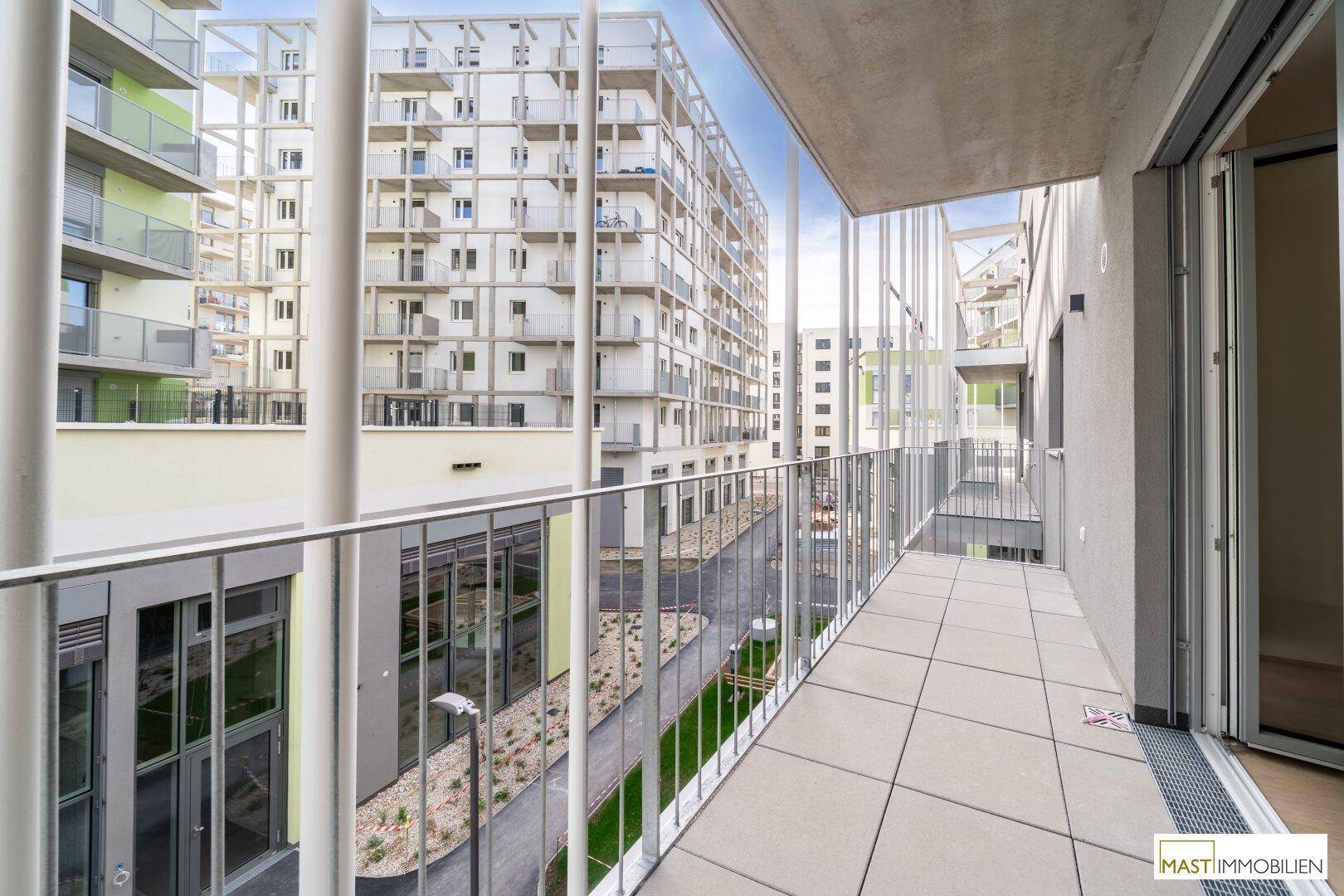 Geräumiger Balkon mit Fliesenboden und Blick auf die moderne Architektur der umliegenden Wohngebäude.